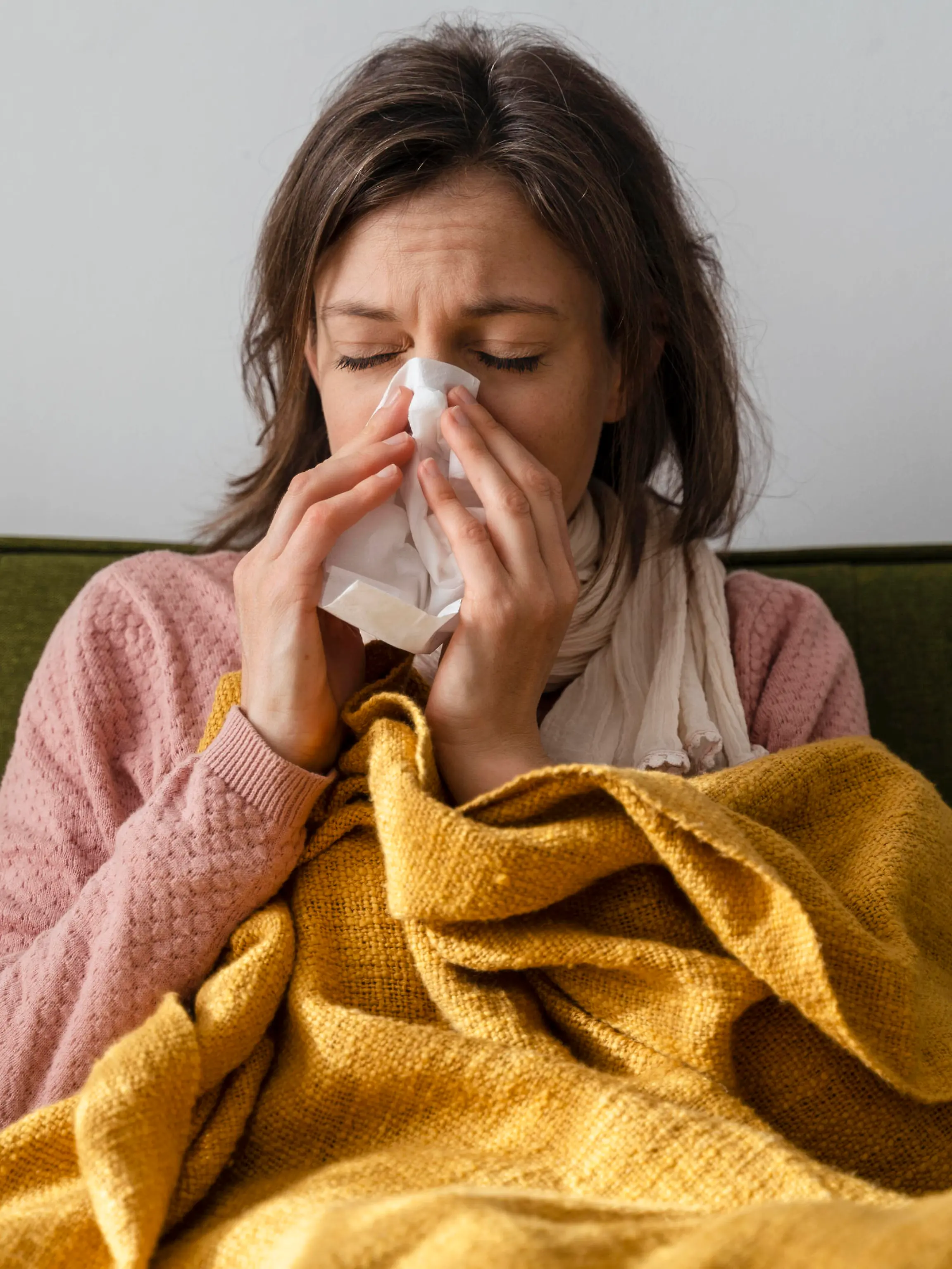 Sick woman blowing nose in facial tissue sitting on sofa at home model released, Symbolfoto property released, DIGF17732