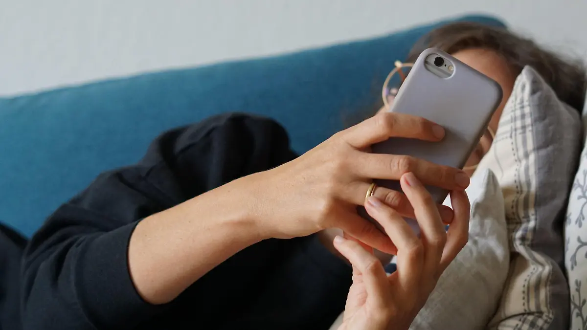 ARCHIV - 28.09.2023, Berlin: Eine junge Frau liegt auf einem Sofa und schaut auf ihr Smartphone. (zu dpa: «Ghosting: Wenn sich eine Bekanntschaft in Luft auflöst») Foto: Weronika Peneshko/dpa +++ dpa-Bildfunk +++