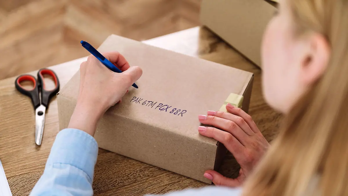Die Paket-ID wird mit einem dunklen Stift auf die Oberseite der Sendung aufgeschrieben.