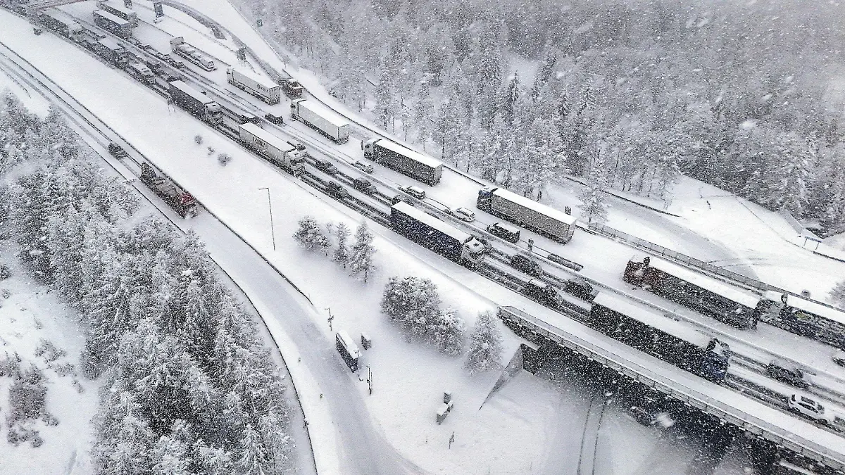 23.02.2024, Österreich, Brenner: Eingeschneite LKWs stehen auf der Autobahn im Stau. Starke Schneefälle haben auf der Brennerautobahn (A13) in Tirol zu einer vorläufigen Komplettsperre in Richtung Süden geführt. Foto: Markus Angerer/APA/dpa +++ dpa-Bildfunk +++