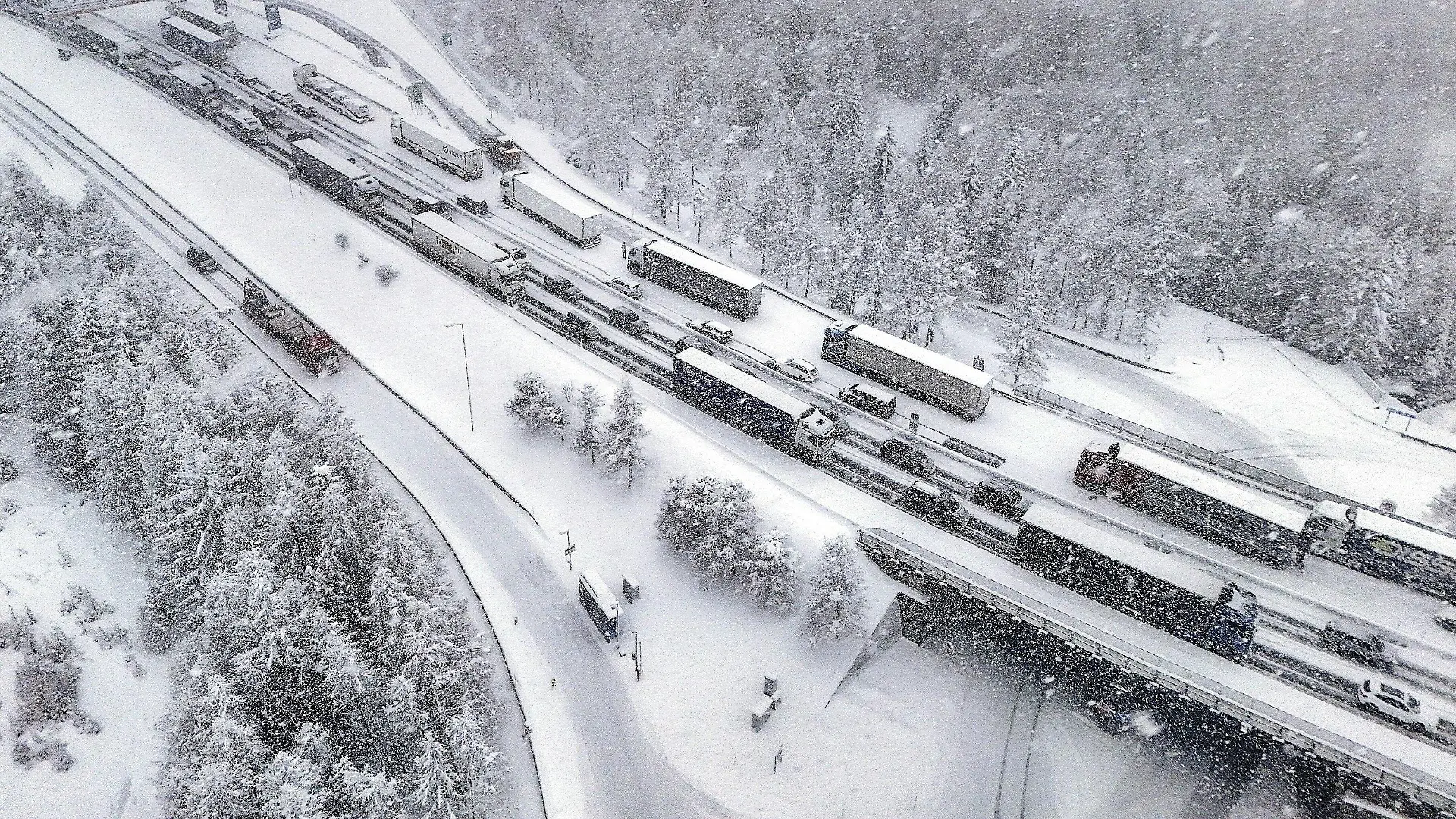 23.02.2024, Österreich, Brenner: Eingeschneite LKWs stehen auf der Autobahn im Stau. Starke Schneefälle haben auf der Brennerautobahn (A13) in Tirol zu einer vorläufigen Komplettsperre in Richtung Süden geführt. Foto: Markus Angerer/APA/dpa +++ dpa-Bildfunk +++