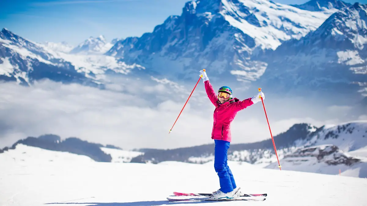Young active woman skiing in mountains. Female skier kid with safety helmet, goggles and poles enjoying sunny winter day in Swiss Alps. Ski race for adults. Winter and snow sport in alpine resort.