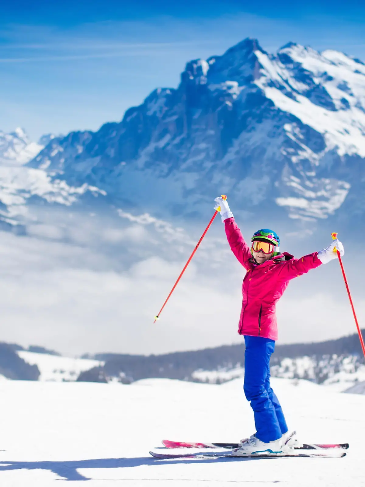 Young active woman skiing in mountains. Female skier kid with safety helmet, goggles and poles enjoying sunny winter day in Swiss Alps. Ski race for adults. Winter and snow sport in alpine resort.