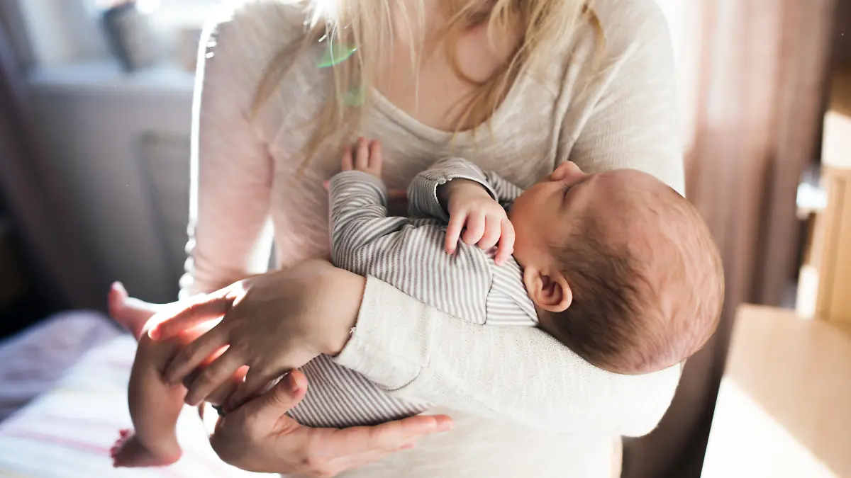 Unrecognizable young mother holding her baby son in her arms