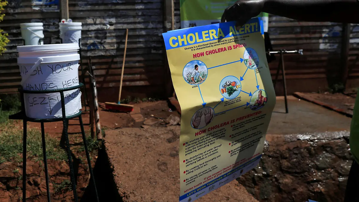 FILE PHOTO: A man holds an information poster about cholera outside a tent at Kuwadzana Polyclinic in Harare, Zimbabwe November 24, 2023. REUTERS/Philimon Bulawayo/File Photo
