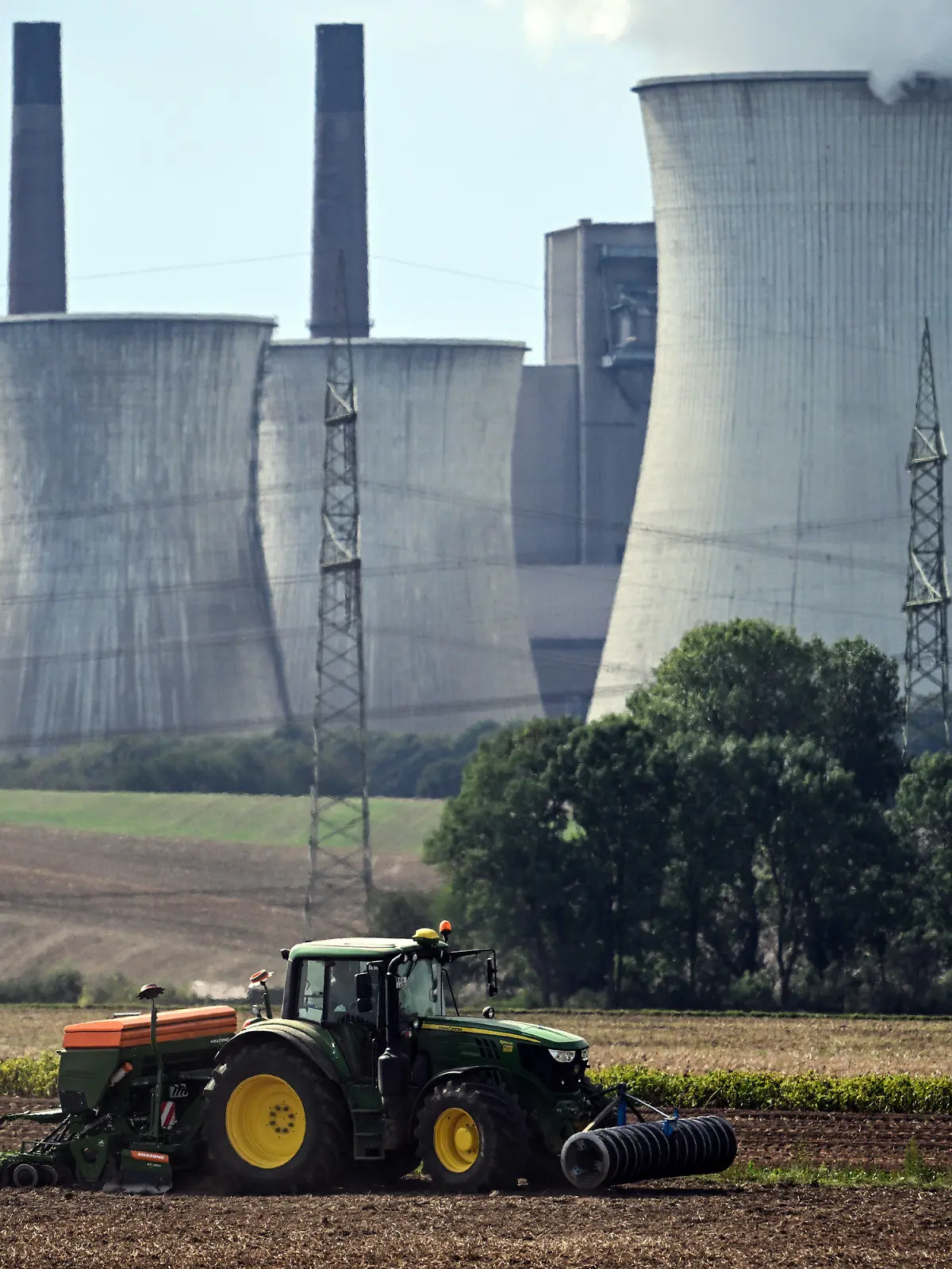 13.09.2022, Nordrhein-Westfalen, Allrath: Ein Landwirt nutzt das sonnige Wetter um vor der Kulisse des Braunkohlekraftwerks Neurath sein Feld zu bestellen. (Zu dpa "Gas sparen: Ältere Braunkohlekraftwerke dürfen wieder Strom erzeugen") Foto: Federico Gambarini/dpa +++ dpa-Bildfunk +++