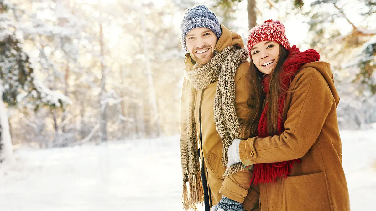 Happy couple in winterwear taking walk in forest