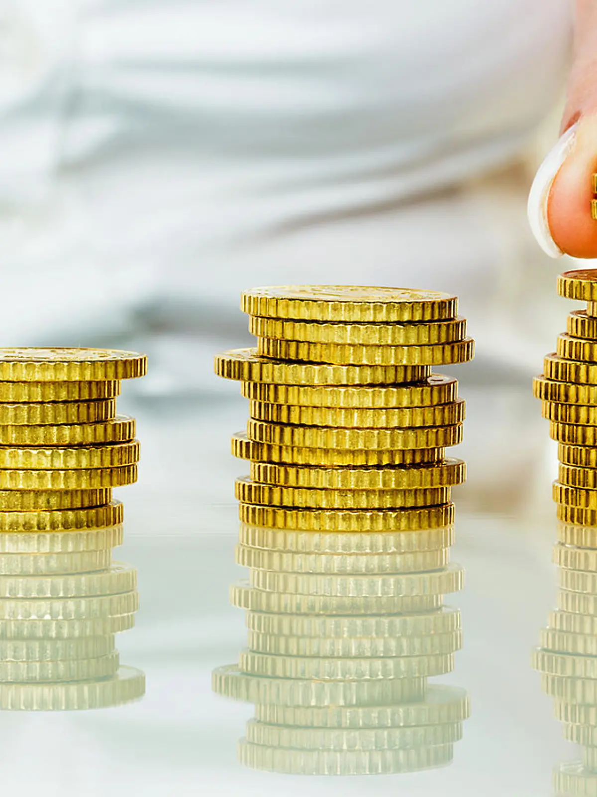 Eine Frau stapelt MÃ¼nzen. Geld sparen fÃ¼r die Zukunft.