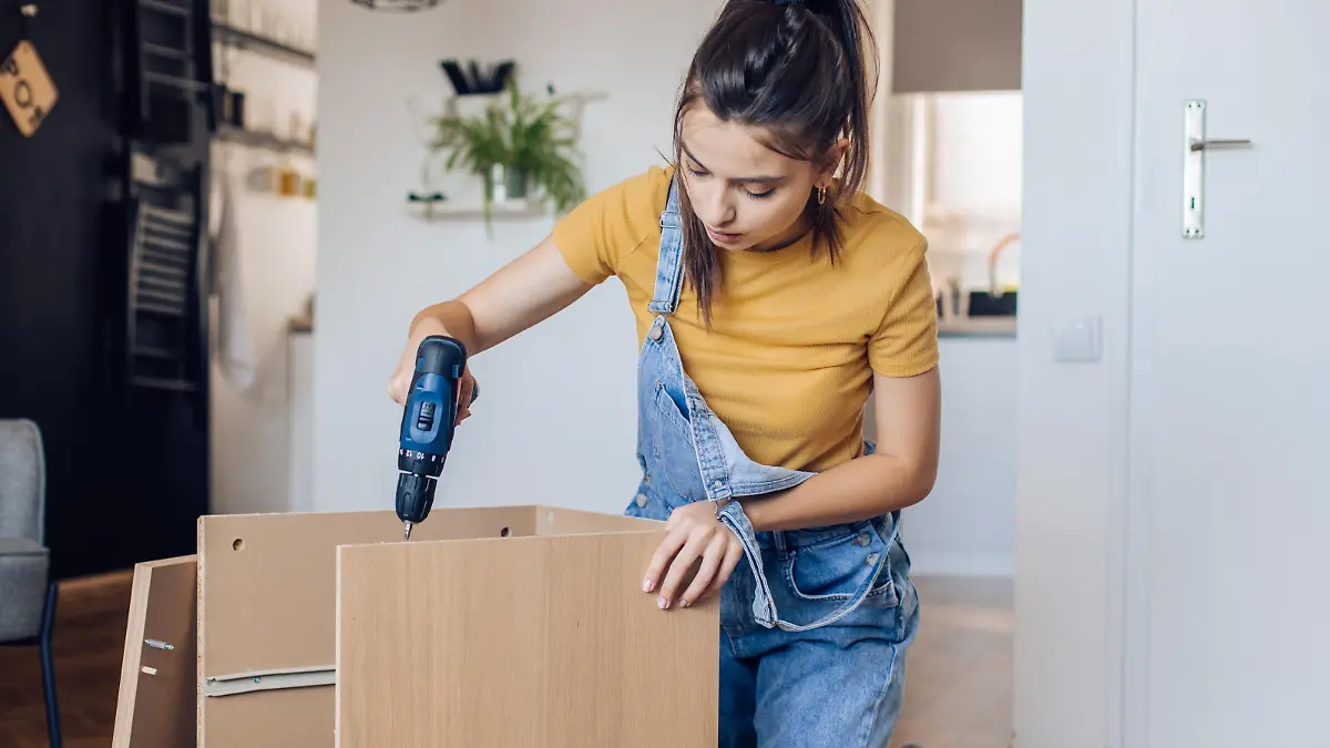 Teenage girl folding wooden furniture at home.