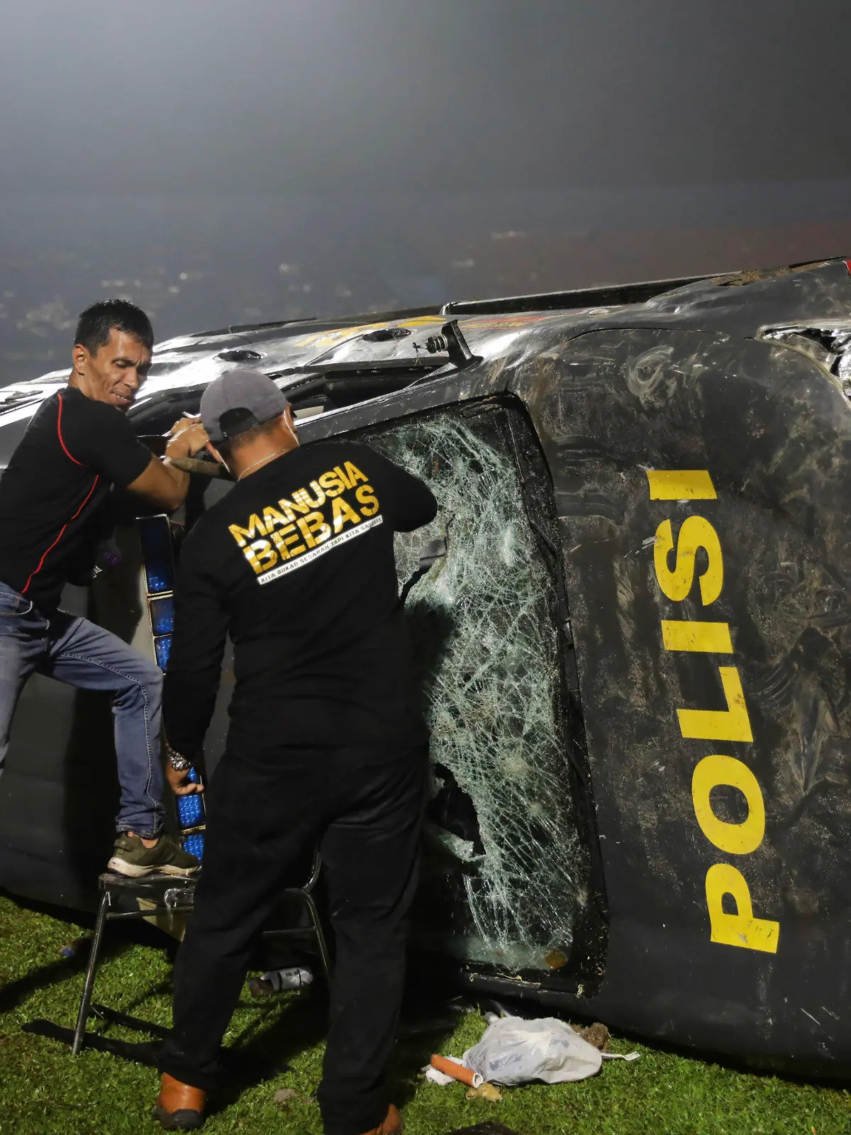 01.10.2022, Indonesien, Malang: Beamte untersuchen ein beschädigtes Polizeifahrzeug nach Zusammenstößen zwischen Anhängern nach dem Erstliga im Kanjuruhan-Stadion. Bei schweren Ausschreitungen im Anschluss an ein Fußball-Spiel in der indonesischen Provinz Ost-Java sind mindestens 127 Menschen ums Leben gekommen. Foto: Yudha Prabowo/AP/dpa +++ dpa-Bildfunk +++