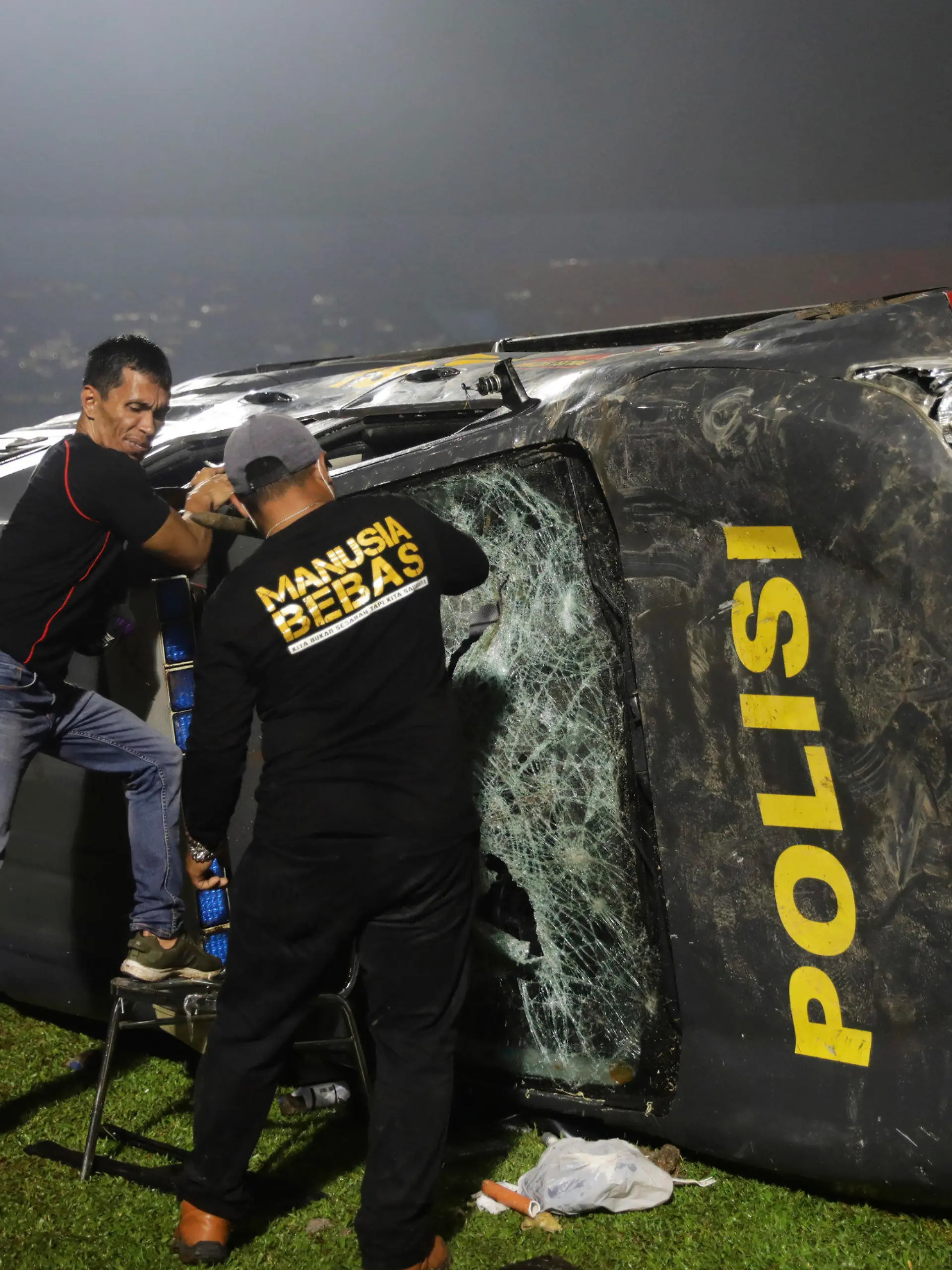 01.10.2022, Indonesien, Malang: Beamte untersuchen ein beschädigtes Polizeifahrzeug nach Zusammenstößen zwischen Anhängern nach dem Erstliga im Kanjuruhan-Stadion. Bei schweren Ausschreitungen im Anschluss an ein Fußball-Spiel in der indonesischen Provinz Ost-Java sind mindestens 127 Menschen ums Leben gekommen. Foto: Yudha Prabowo/AP/dpa +++ dpa-Bildfunk +++
