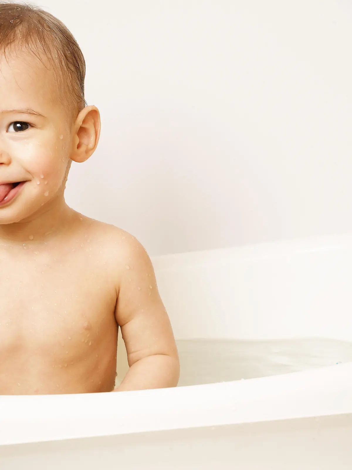 Adorable smiling little boy is sticking a tongue while taking a bath in warm water. || Modellfreigabe vorhanden