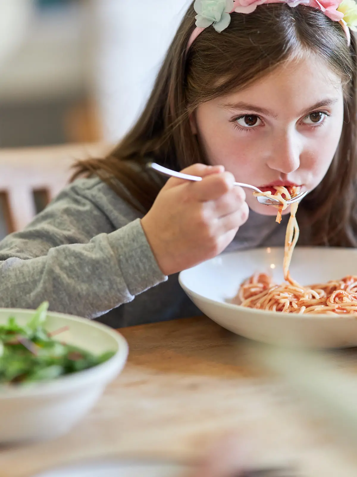 Hungriges Kind beim Spaghetti essen mit Tomatensauce beim Abendessen