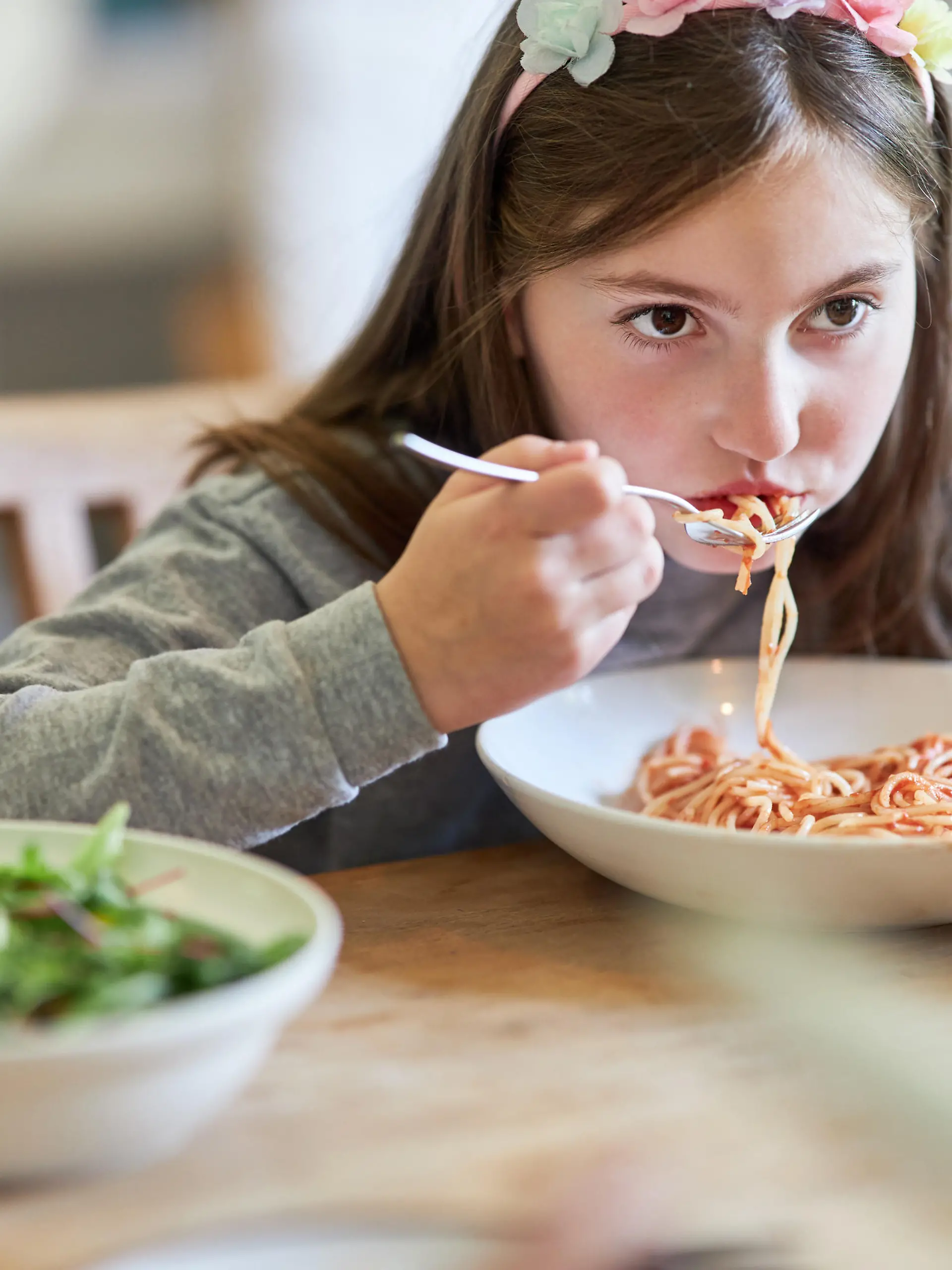 Hungriges Kind beim Spaghetti essen mit Tomatensauce beim Abendessen