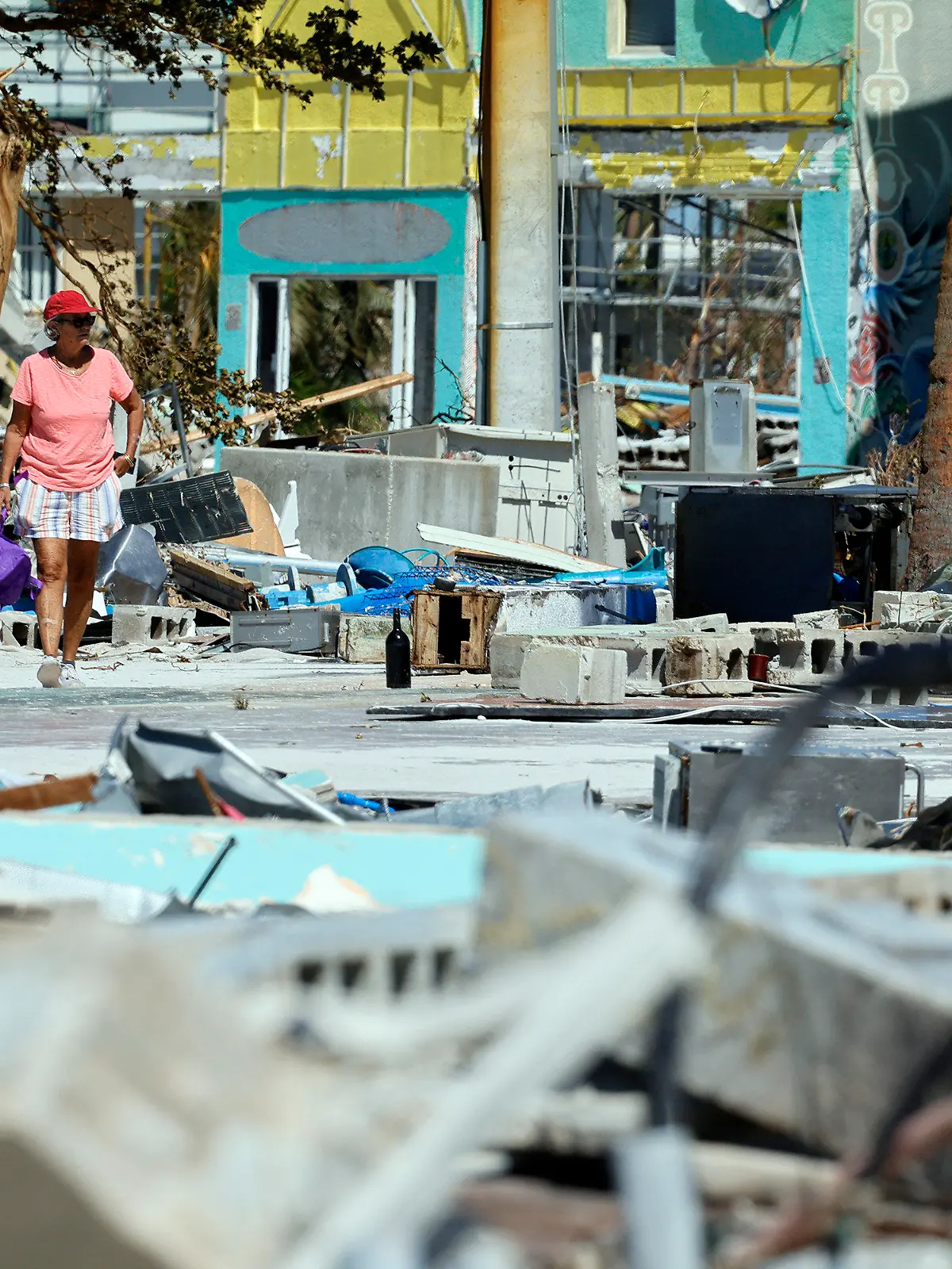 Ana Kapel walks through what is left of the Times Square area near the Lynn Hall Pier on the island of Fort Myers Beach, Fla., Friday, Sept. 30, 2022. Hurricane Ian made landfall Wednesday, Sept. 28, 2022, as a Category 4 hurricane on the southwest coast of Florida. (Amy Beth Bennett/South Florida Sun-Sentinel via AP)