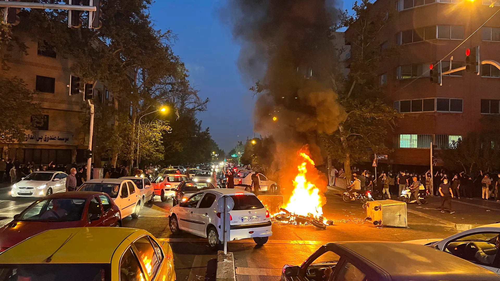 19.09.2022, Iran, Tehran: Auf diesem Bild vom Montag, 19. September 2022, das von einer nicht bei Associated Press angestellten Person aufgenommen und von AP außerhalb des Irans beschafft wurde, brennt ein Polizeimotorrad während eines Protests gegen den Tod einer jungen Frau, die festgenommen wurde, weil sie gegen die konservative Kleiderordnung des Landes verstoßen hatte, in der Innenstadt von Teheran, Iran. Nach dem Tod der 22-jährigen Mahsa Amini im Polizeigewahrsam haben in der iranischen Hauptstadt Teheran Tausende Menschen protestiert. (zu dpa: «Tausende demonstrieren im Iran nach Tod von Mahsa Amini») Foto: Uncredited/AP/dpa +++ dpa-Bildfunk +++