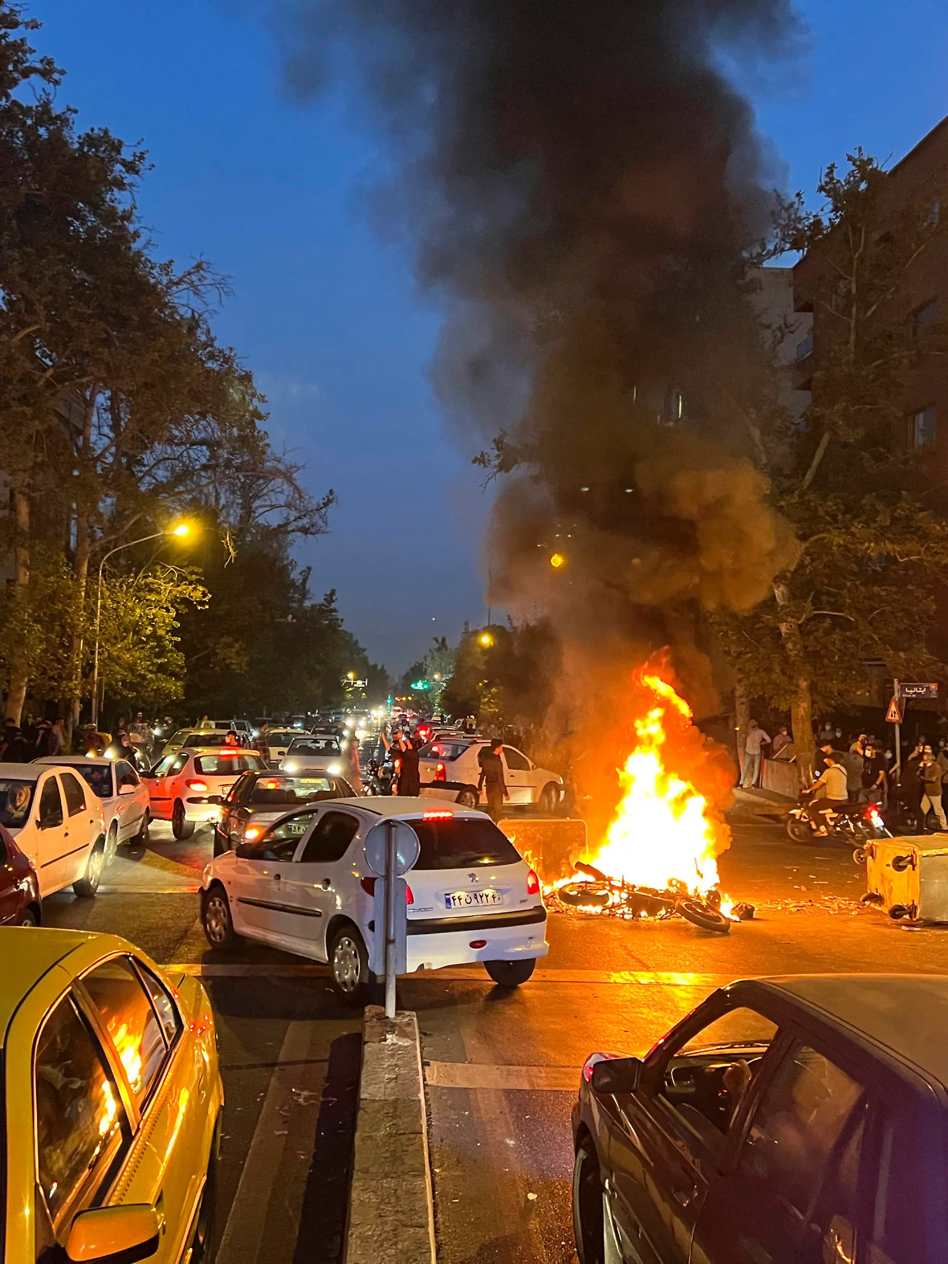 19.09.2022, Iran, Tehran: Auf diesem Bild vom Montag, 19. September 2022, das von einer nicht bei Associated Press angestellten Person aufgenommen und von AP außerhalb des Irans beschafft wurde, brennt ein Polizeimotorrad während eines Protests gegen den Tod einer jungen Frau, die festgenommen wurde, weil sie gegen die konservative Kleiderordnung des Landes verstoßen hatte, in der Innenstadt von Teheran, Iran. Nach dem Tod der 22-jährigen Mahsa Amini im Polizeigewahrsam haben in der iranischen Hauptstadt Teheran Tausende Menschen protestiert. (zu dpa: «Tausende demonstrieren im Iran nach Tod von Mahsa Amini») Foto: Uncredited/AP/dpa +++ dpa-Bildfunk +++