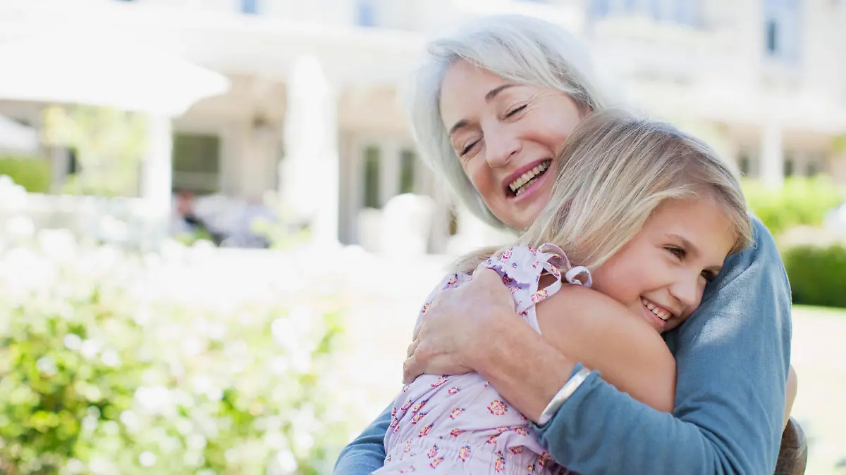 Grandmother and granddaughter hugging in backyard