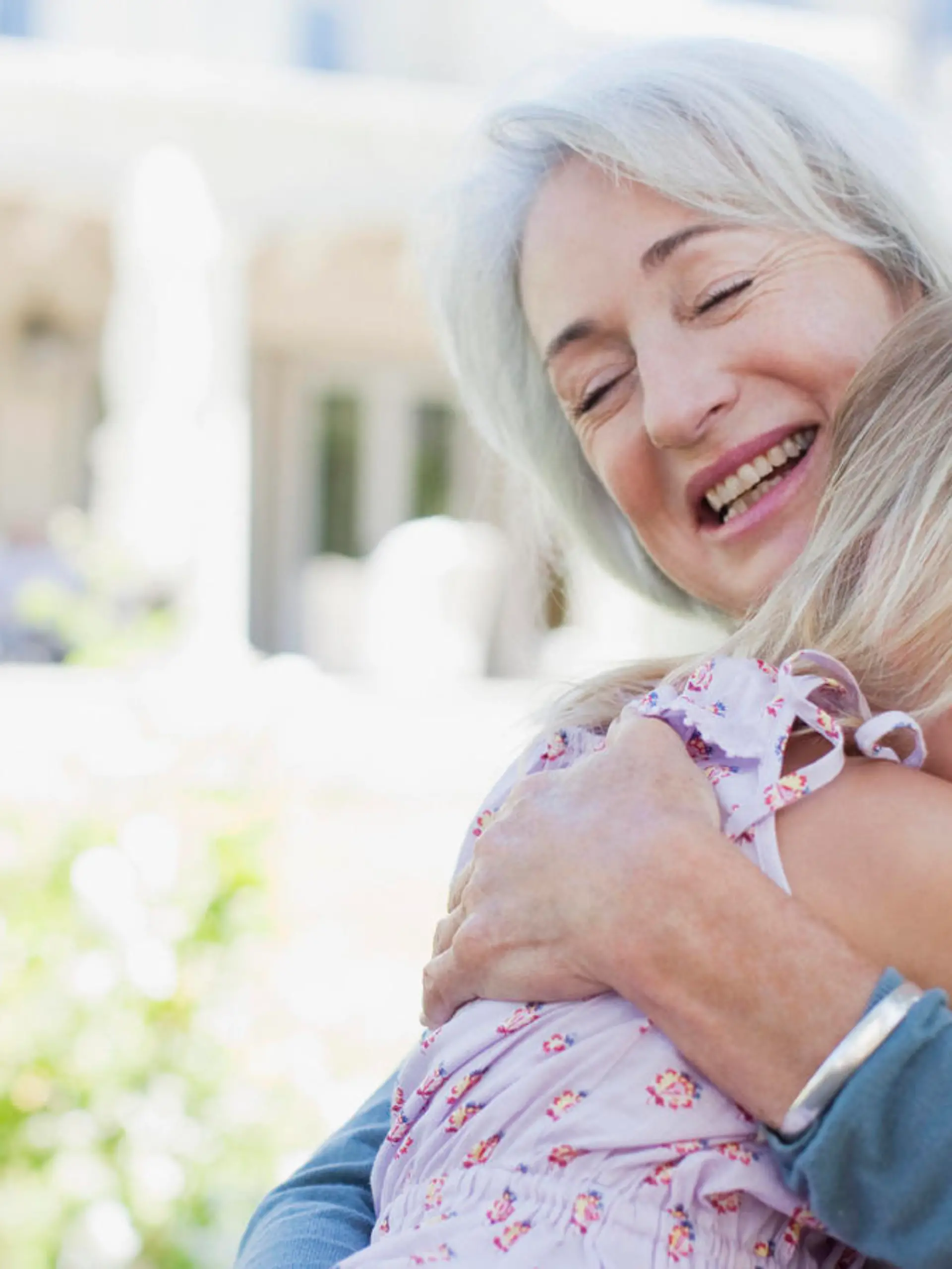 Grandmother and granddaughter hugging in backyard