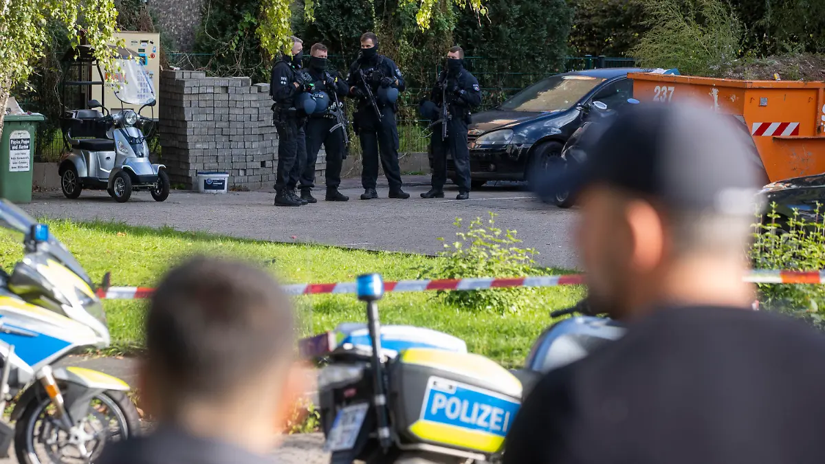 30.09.2022, Nordrhein-Westfalen, Dormagen: Polizisten stehen im Stadtteil Hackenbroich vor einem Kiosk. Hier wurde ein Mann erschossen. Die Polizei fahndete mit Dutzenden Beamten nach dem Schützen und nahm die Spurensicherung auf. Foto: Christoph Reichwein/dpa +++ dpa-Bildfunk +++