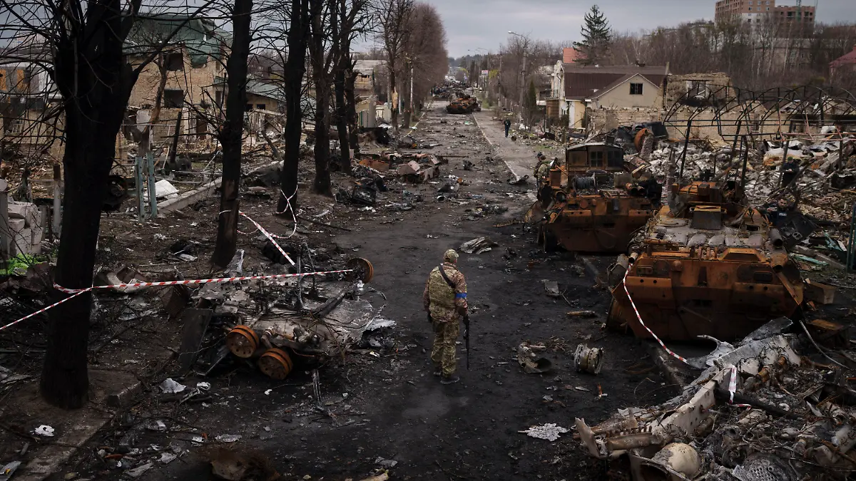 06.04.2022, Ukraine, Butscha: Ein ukrainischer Soldat steht neben zerstörten russischen Panzer in Butscha am Stadtrand von Kiew. Foto: Felipe Dana/AP/dpa +++ dpa-Bildfunk +++