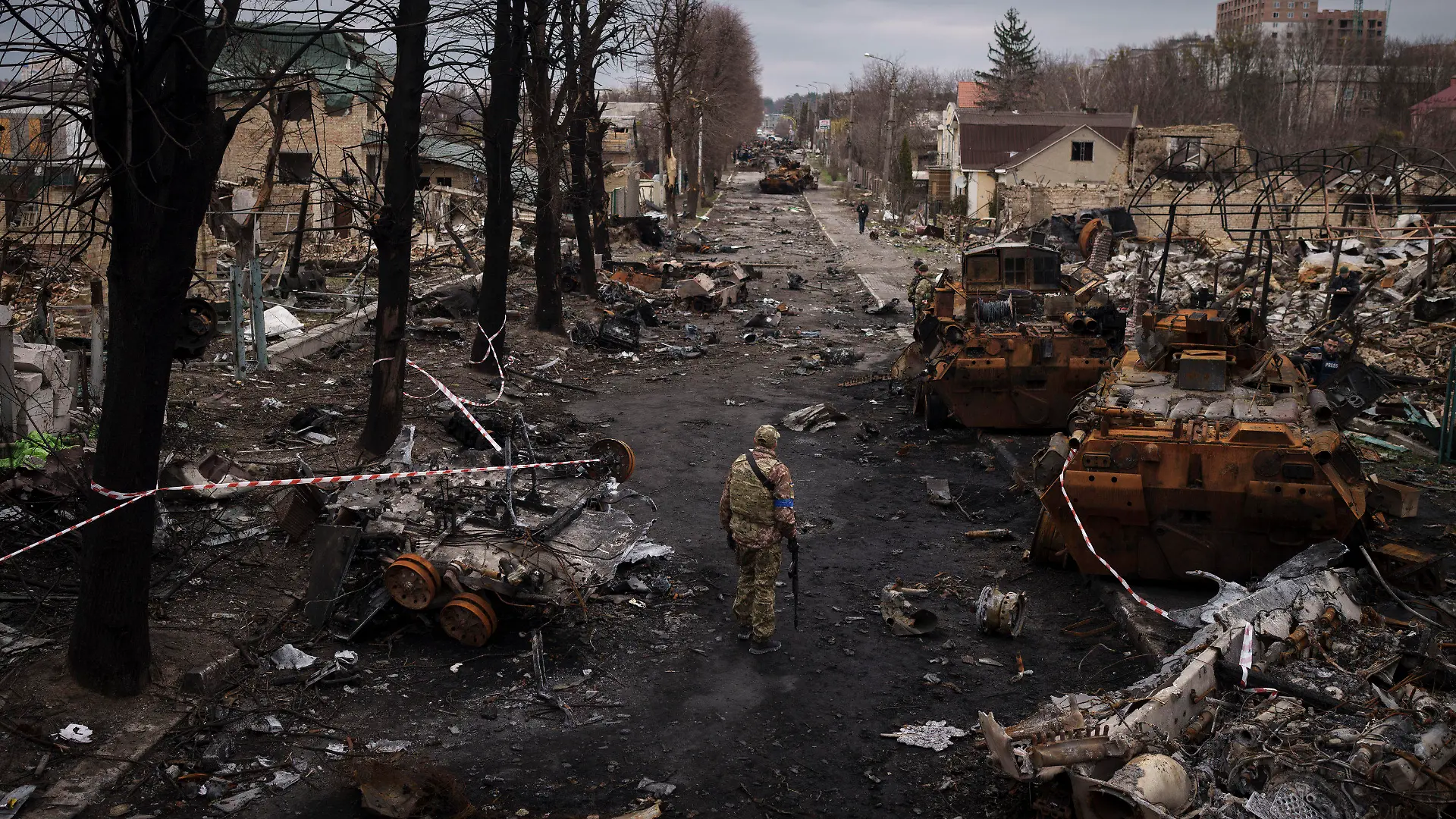 06.04.2022, Ukraine, Butscha: Ein ukrainischer Soldat steht neben zerstörten russischen Panzer in Butscha am Stadtrand von Kiew. Foto: Felipe Dana/AP/dpa +++ dpa-Bildfunk +++