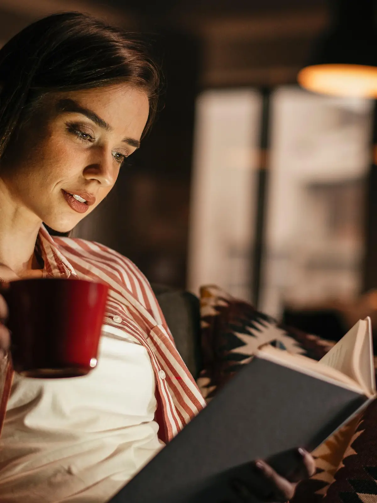 Frau liest Horrorbuch im Dunkeln.