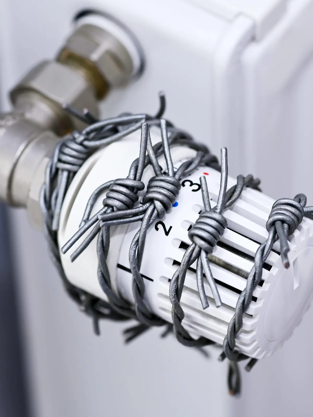 Mit Stacheldraht umwickeltes Heizungsthermostat, Symbolfoto Heizkosten und Gaskrise *** Heating thermostat wrapped with barbed wire, symbol photo heating costs and gas crisis 