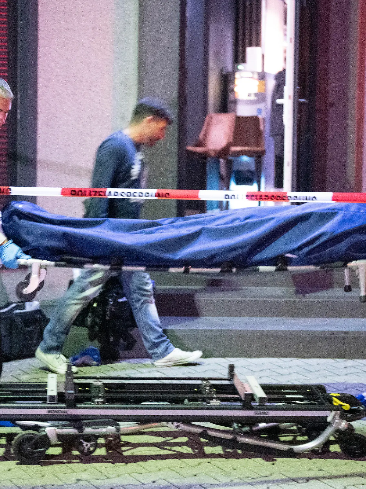 11.09.2022, Hessen, Offenbach am Main: Bestatter tragen die Leiche eines Opfers aus einer Bar in Offenbach. Die Person war durch einen Schuss tödlich verletzt worden, eine weitere Person wurde nach Angaben der Polizei schwer verletzt. Der oder die Täter sind flüchtig. Foto: Boris Roessler/dpa +++ dpa-Bildfunk +++