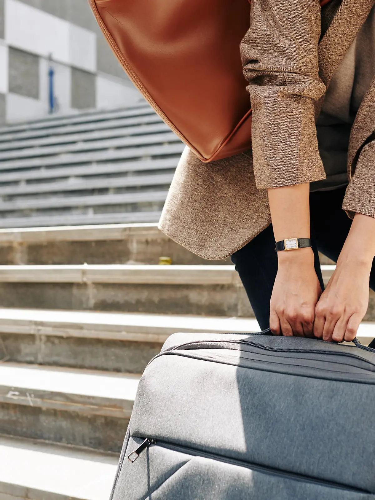 Cropped image of woman pulling big suitcase when walking up the stairs to railway station