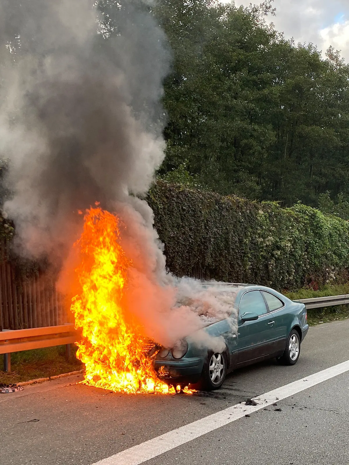 HANDOUT - 29.09.2022, Bayern, Weiden: Ein grünes Auto brennt auf der Autobahn 93. Laut Polizei hatte sich der 20 Jahre alte Fahrer des Wagens zuvor ein Rennen gegen seine Mutter geliefert.      (zu dpa «Betrunken und ohne Führerschein - Sohn fährt Autorennen gegen Mutter») Foto: Polizeiinspektion Marktredwitz/dpa - ACHTUNG: Nur zur redaktionellen Verwendung im Zusammenhang mit der aktuellen Berichterstattung und nur mit vollständiger Nennung des vorstehenden Credits +++ dpa-Bildfunk +++