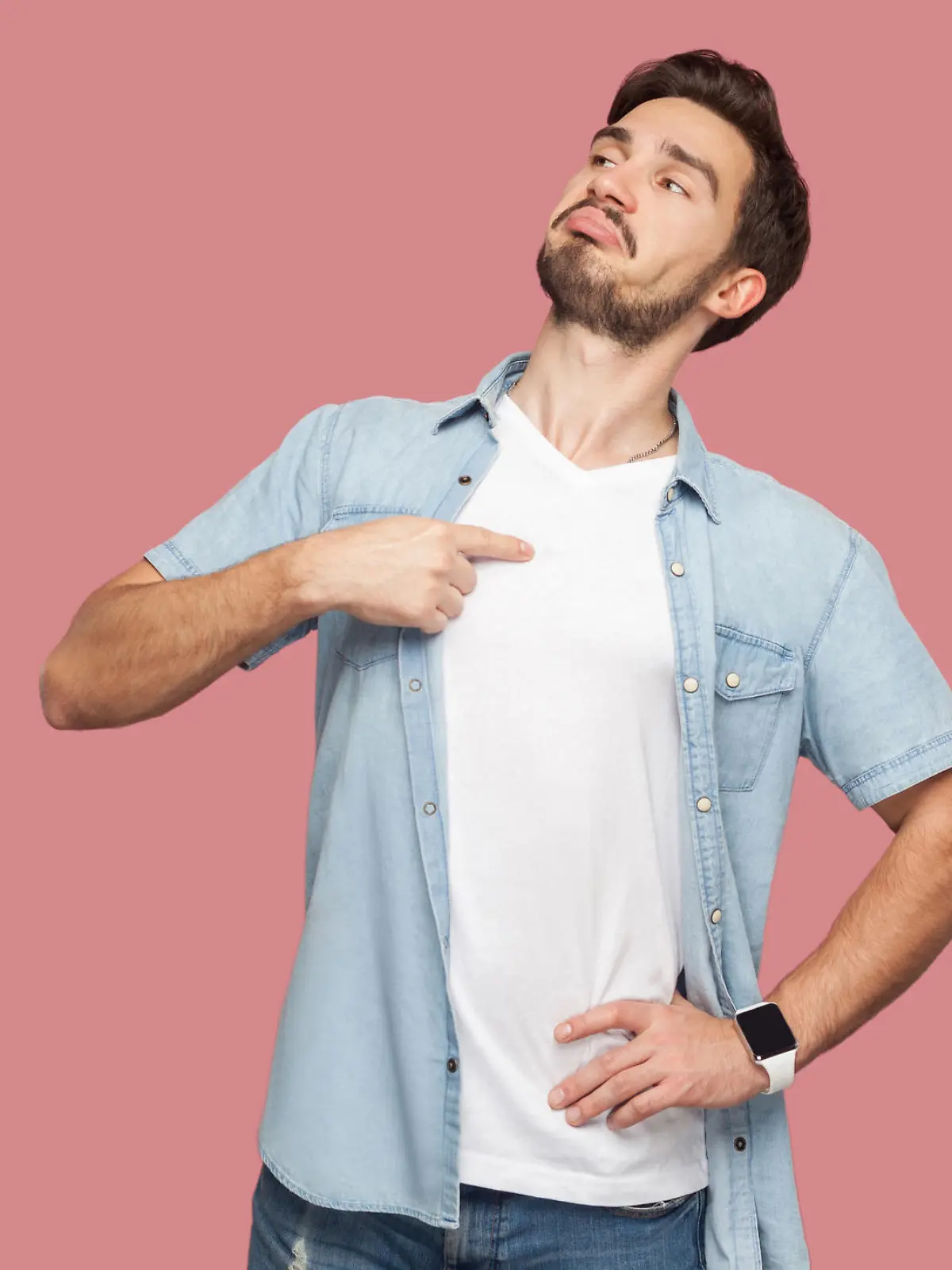This is me. Portrait of proud haughty handsome bearded young man in blue casual style shirt standing, looking away and pointing himself. indoor studio shot, isolated on pink background.