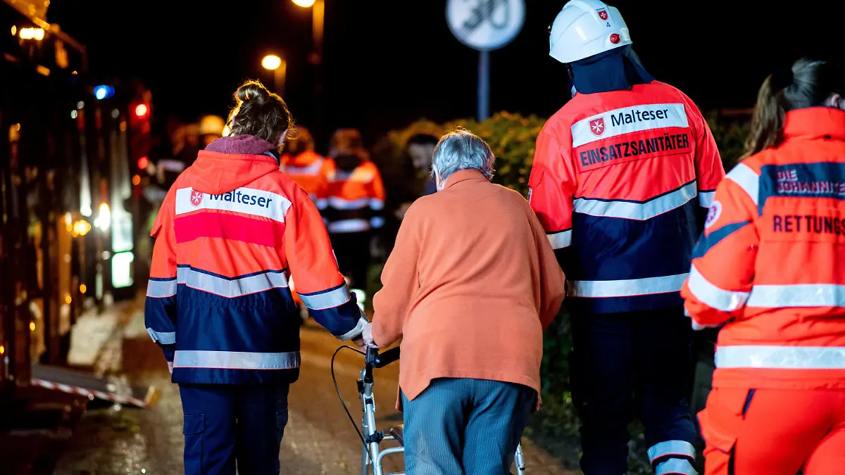 25.09.2022, Niedersachsen, Wardenburg: Einsatzsanitäter des Malteser Hilfsdienstes bringen die Bewohner eines Altenheims im Ortsteil Südmoslesfehn zu einem Bus, mit dem sie zu einer Notunterkunft gebracht werden sollen. Bei einem Feuer in einem Altenheim in Wardenburg bei Oldenburg sind drei Menschen ums Leben gekommen. Sie starben vermutlich durch Rauchgase, sagte ein Feuerwehrsprecher am Sonntag. Foto: Hauke-Christian Dittrich/dpa +++ dpa-Bildfunk +++