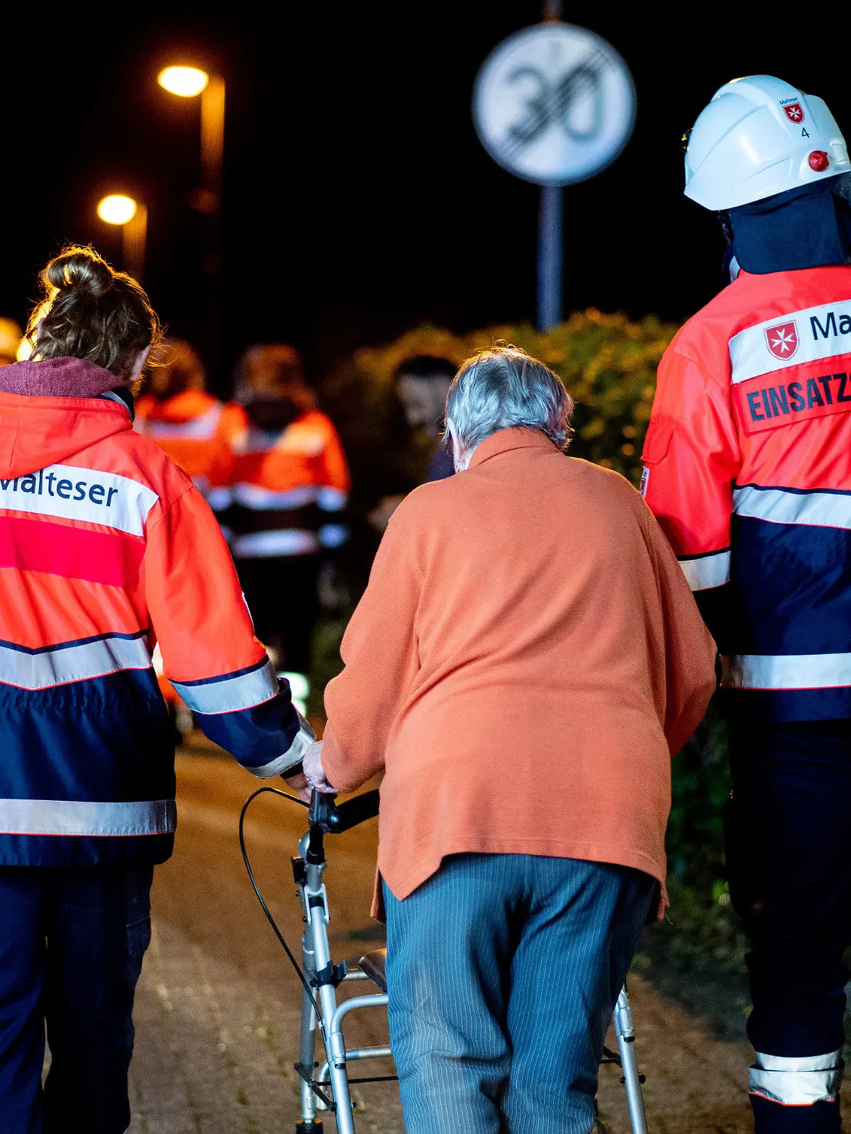 25.09.2022, Niedersachsen, Wardenburg: Einsatzsanitäter des Malteser Hilfsdienstes bringen die Bewohner eines Altenheims im Ortsteil Südmoslesfehn zu einem Bus, mit dem sie zu einer Notunterkunft gebracht werden sollen. Bei einem Feuer in einem Altenheim in Wardenburg bei Oldenburg sind drei Menschen ums Leben gekommen. Sie starben vermutlich durch Rauchgase, sagte ein Feuerwehrsprecher am Sonntag. Foto: Hauke-Christian Dittrich/dpa +++ dpa-Bildfunk +++