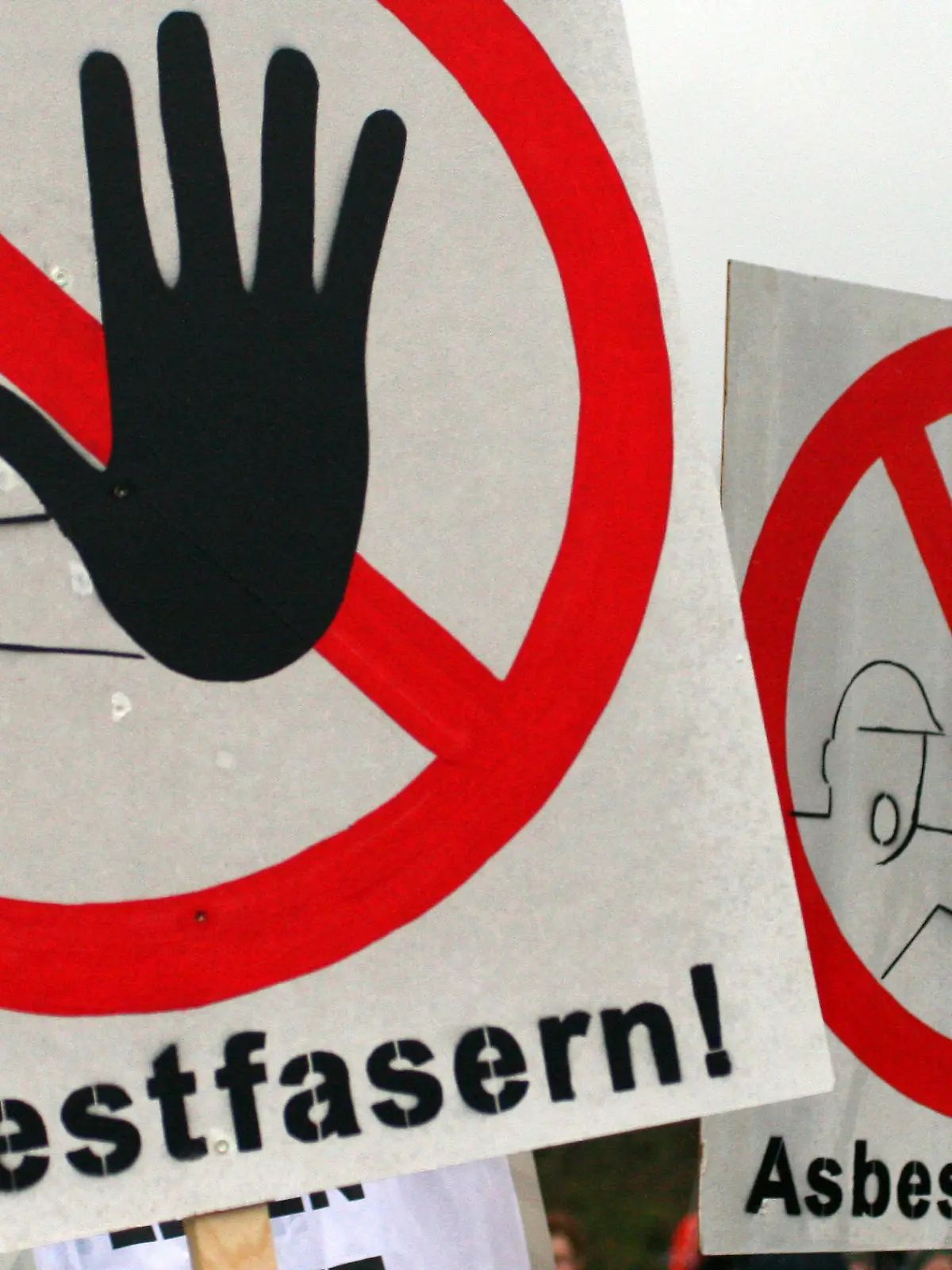 ARCHIV - 27.11.2011, Rondeshagen: Warnschilder vor Asbestfasern sind  während einer Demonstration zu sehen. Das gesundheitsgefährdende Material Asbest schlummert im Verborgenen, rund ein Viertel aller Gebäude mit Bau- oder Sanierungsjahr vor 1994 könnte belastet sein. Jüngst wurde in Hamburg mehrfach Alarm geschlagen. (zu dpa «Gefahrenquelle Asbest: Altlasten schlummern noch immer in Gebäuden») Foto: Daniel Bockwoldt/dpa +++ dpa-Bildfunk +++