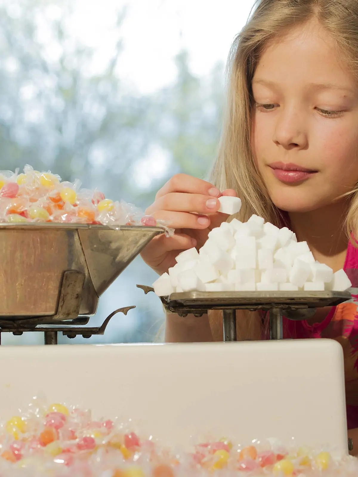  Girl behind scales, weighing sugar cubes and a lot of candies model released Symbolfoto property released PUBLICATIONxINxGERxSUIxAUTxHUNxONLY NEKF00038