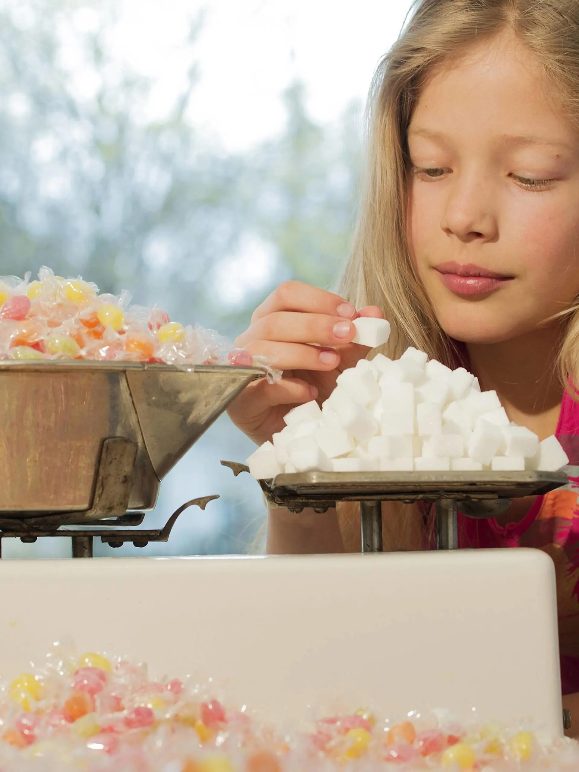  Girl behind scales, weighing sugar cubes and a lot of candies model released Symbolfoto property released PUBLICATIONxINxGERxSUIxAUTxHUNxONLY NEKF00038