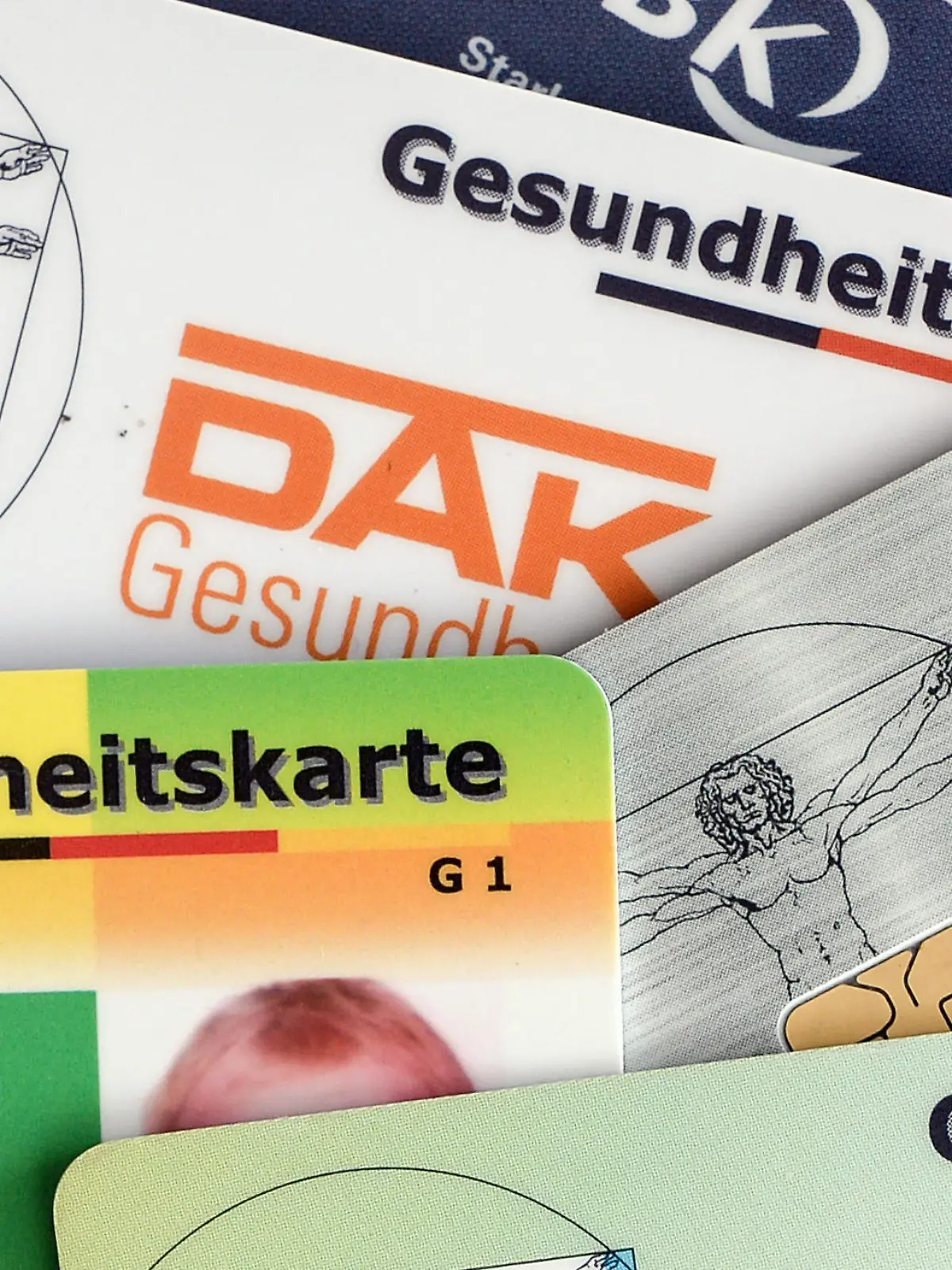 ARCHIV - 17.04.2018, Berlin: Gesundheitskarten verschiedener Krankenkassen liegen auf einem Tisch. Die Mitglieder der gesetzlichen Krankenkassen sollen dauerhaft davor geschützt werden, steigende Gesundheitskosten allein tragen zu müssen. Foto: Jens Kalaene/dpa-Zentralbild/dpa +++ dpa-Bildfunk +++