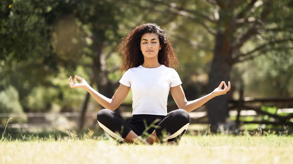 A young woman with long black curly hair doing yoga outdoors / creative PUBLICATIONxINxGERxSUIxAUTxONLY Copyright: javiindyx/xPhotocase photocase_2506656  