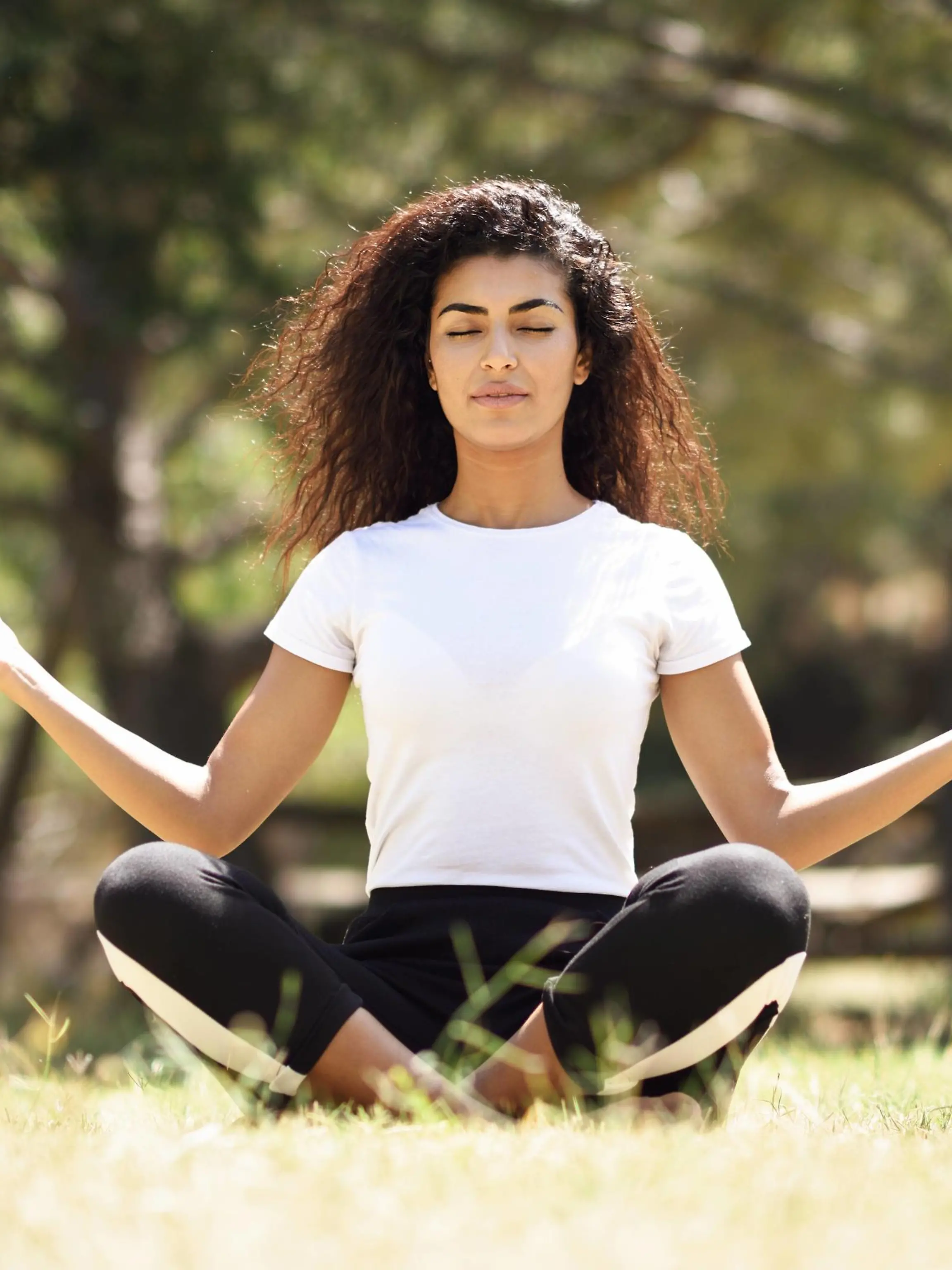 A young woman with long black curly hair doing yoga outdoors / creative PUBLICATIONxINxGERxSUIxAUTxONLY Copyright: javiindyx/xPhotocase photocase_2506656  