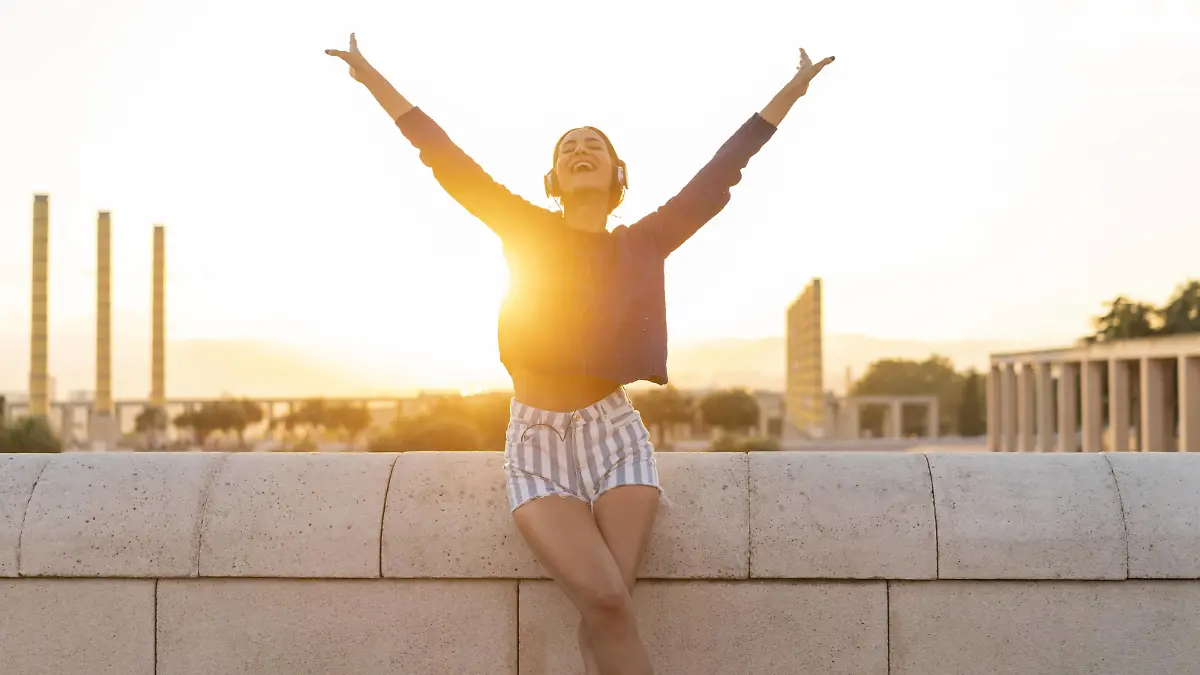 Spain, Barcelona, Montjuic, happy young woman listening to music with headphones at sunset model released Symbolfoto PUBLICATIONxINxGERxSUIxAUTxHUNxONLY AFVF01972  