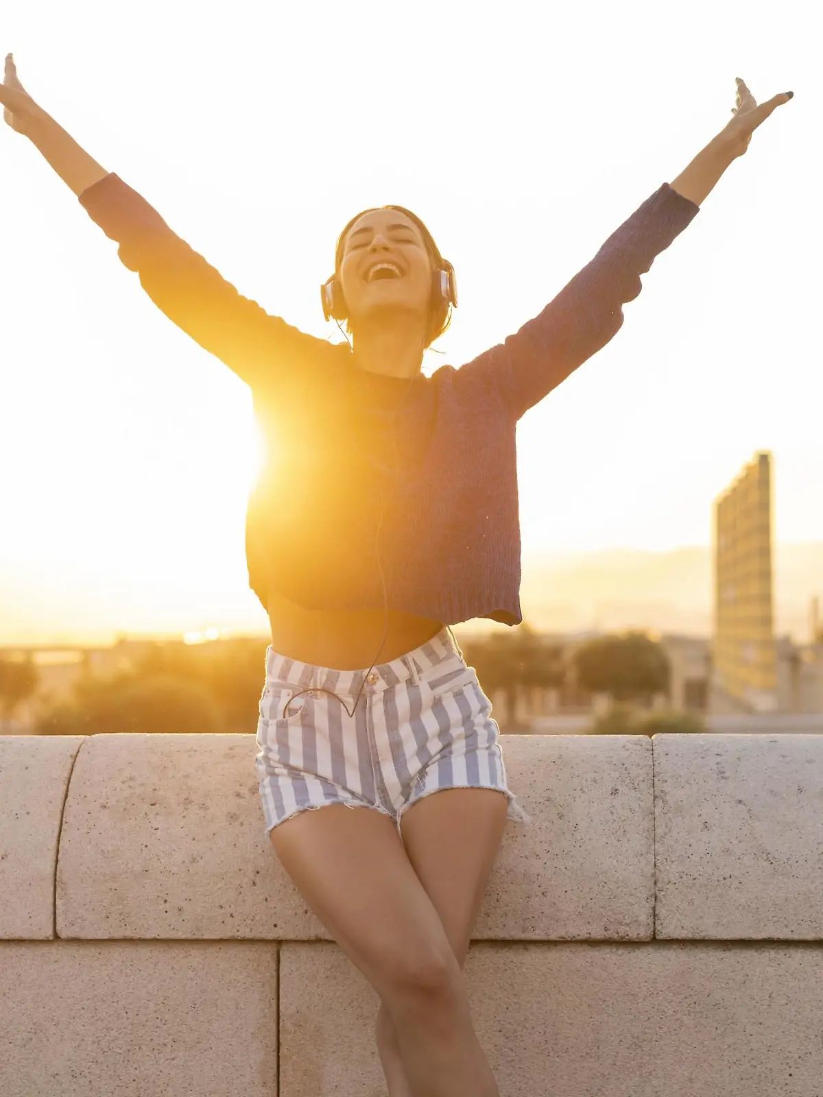 Spain, Barcelona, Montjuic, happy young woman listening to music with headphones at sunset model released Symbolfoto PUBLICATIONxINxGERxSUIxAUTxHUNxONLY AFVF01972  