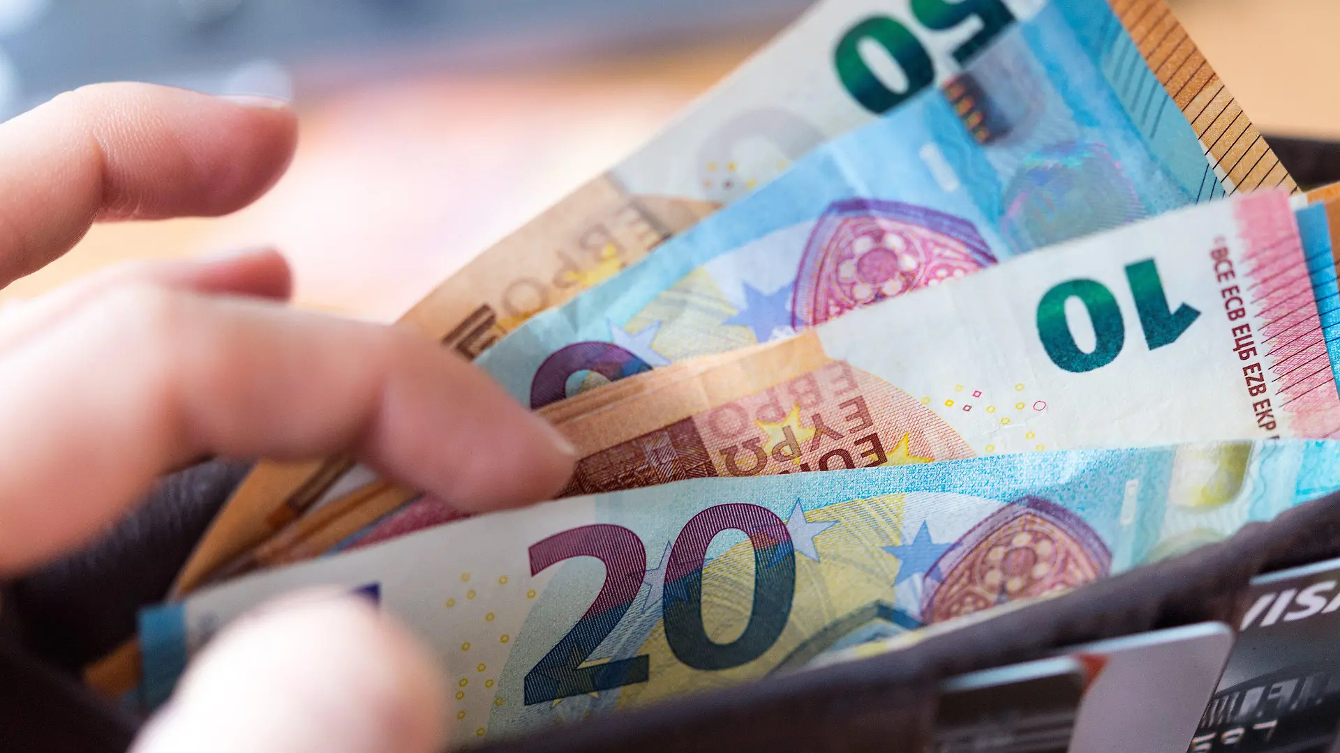 ARCHIV - 04.12.2018, Thüringen, Erfurt: Eine Frau hält eine Geldbörse mit Banknoten in der Hand. In Thüringen haben die Beschäftigten in der Altenpflege nach Angaben des Gesundheitsministeriums den ersten Teil des Corona-Bonus erhalten. (zu dpa: «Ministerium: Erster Teil des Corona-Bonus hat Pflegekräfte erreicht» Foto: Monika Skolimowska/dpa-Zentralbild/dpa +++ dpa-Bildfunk +++