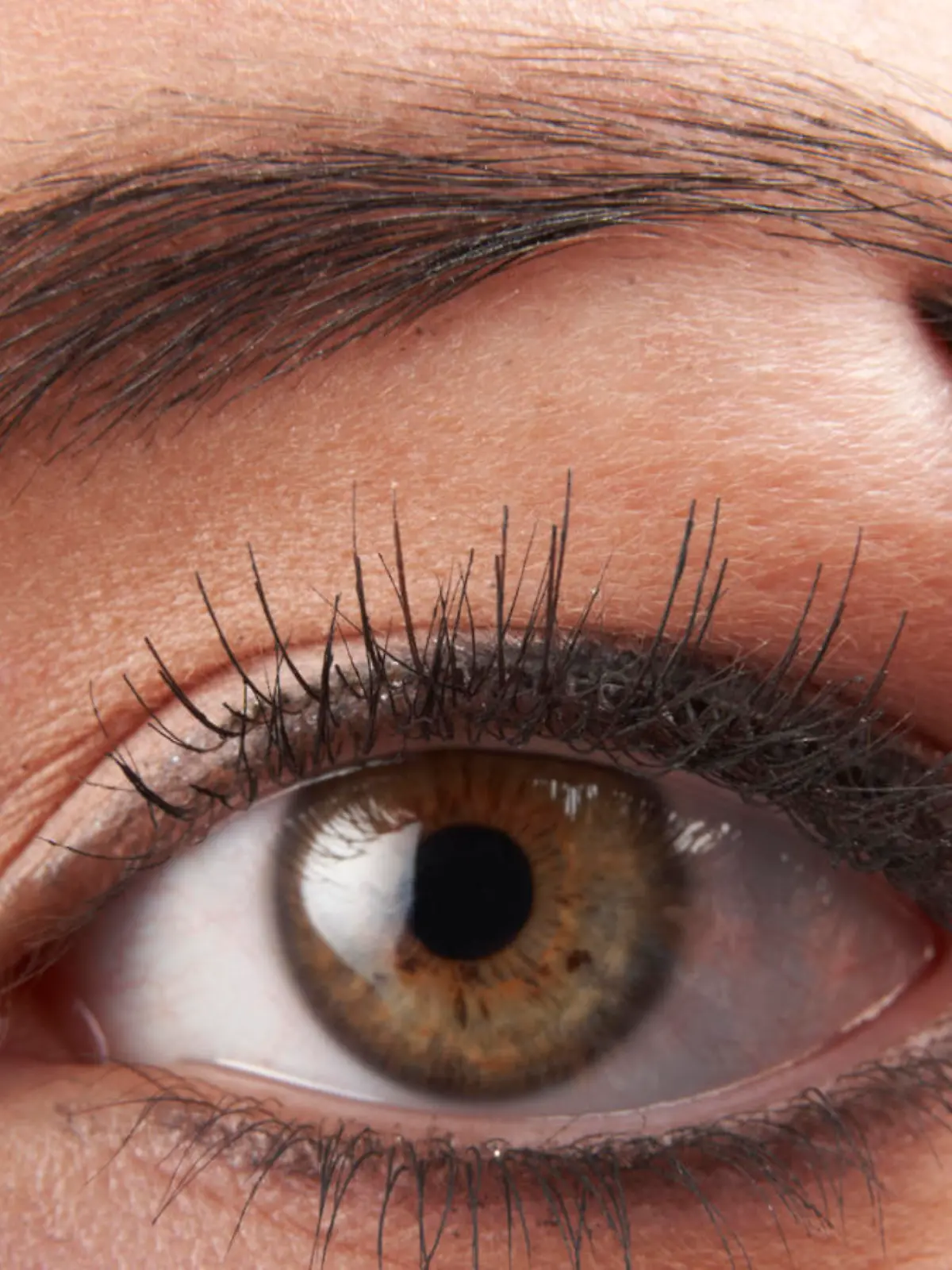 woman applying eye make-up with brush on white background