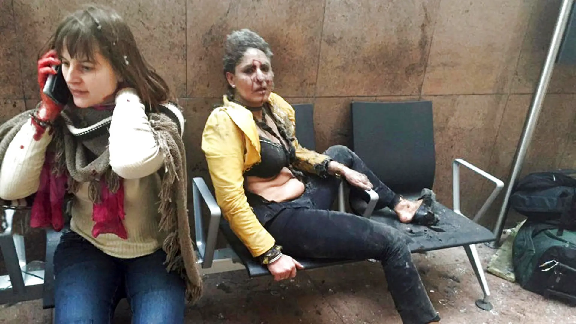 ARCHIV - Die indische Stewardess Nidhi Chaphekar (r) sitzt am 22.03.2016 unmittelbar nach dem Anschlag auf den Flughafen von Brüssel (Belgien) blutüberströmt und geschockt auf einer Flughafenbank. Die belgische Königin Mathilde und König Philippe empfangen Chaphekar am 20.03.2017 in Brüssel. Foto: Ketevan Kardava/AP/dpa +++(c) dpa - Bildfunk+++