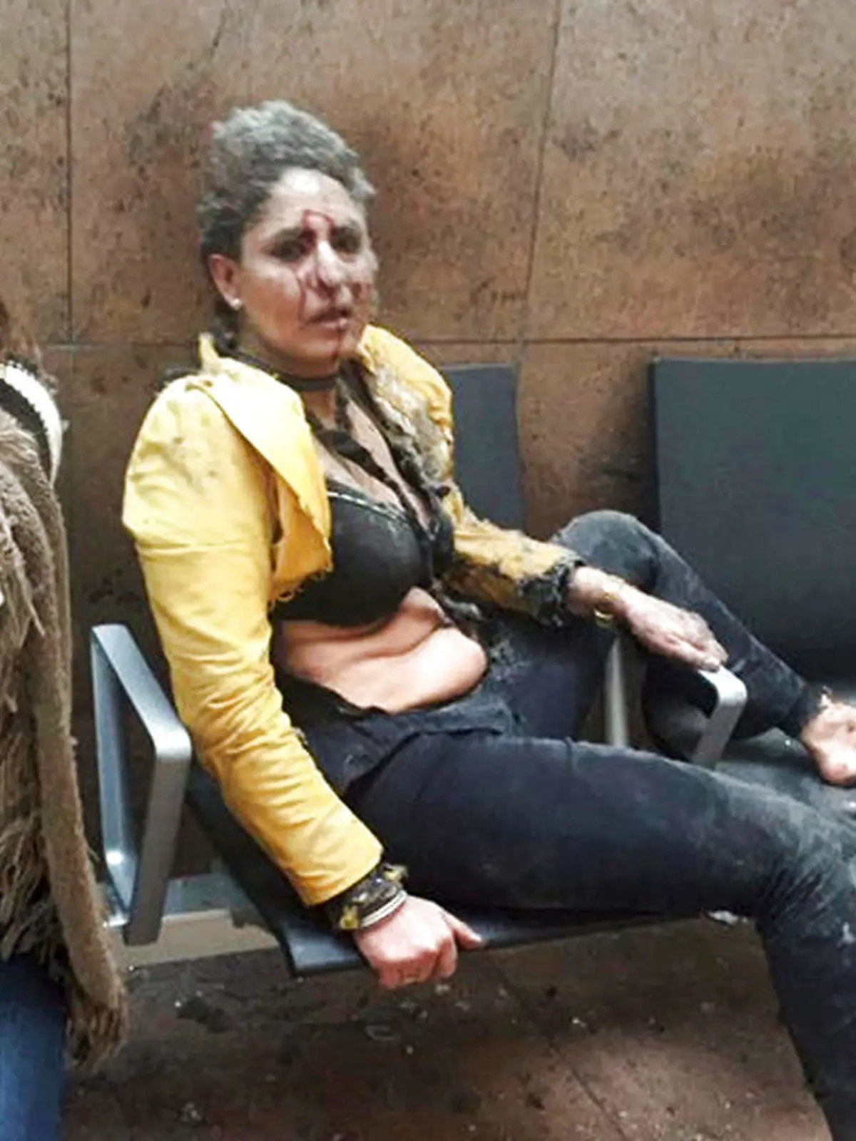 ARCHIV - Die indische Stewardess Nidhi Chaphekar (r) sitzt am 22.03.2016 unmittelbar nach dem Anschlag auf den Flughafen von Brüssel (Belgien) blutüberströmt und geschockt auf einer Flughafenbank. Die belgische Königin Mathilde und König Philippe empfangen Chaphekar am 20.03.2017 in Brüssel. Foto: Ketevan Kardava/AP/dpa +++(c) dpa - Bildfunk+++
