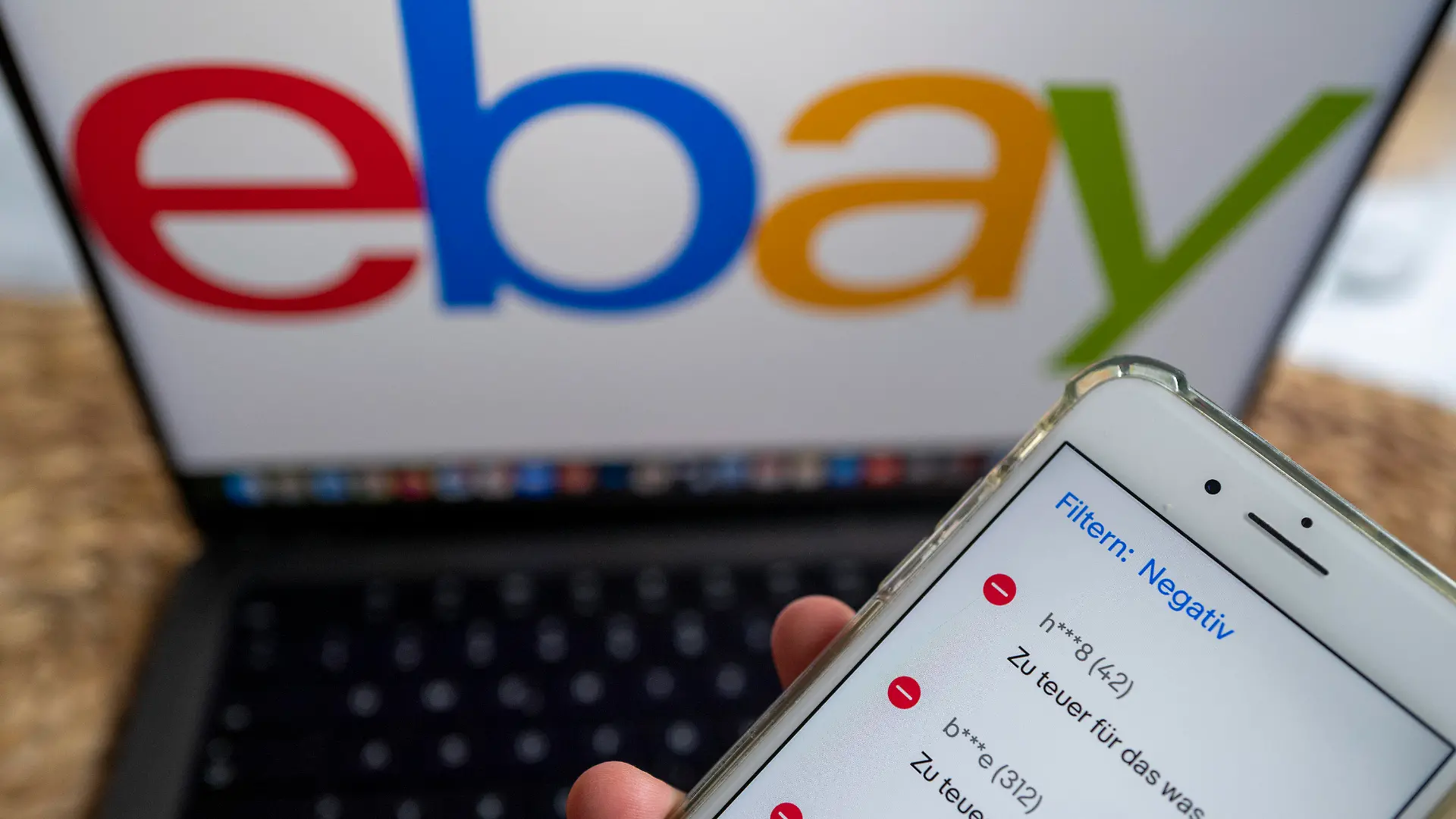 ILLUSTRATION - 26.09.2022, Berlin: ILLUSTRATION - Auf einem Smartphone in der Ebay-App werden negative Bewertungen eines Verkäufers angezeigt, während im Hintergrund das Logo der Verkaufsplattform Ebay zu sehen ist. Der Bundesgerichtshof prüft derzeit, wann Ebay-Verkäufer Anspruch auf Entfernung von negativen Bewertungen haben. Foto: Monika Skolimowska/dpa +++ dpa-Bildfunk +++