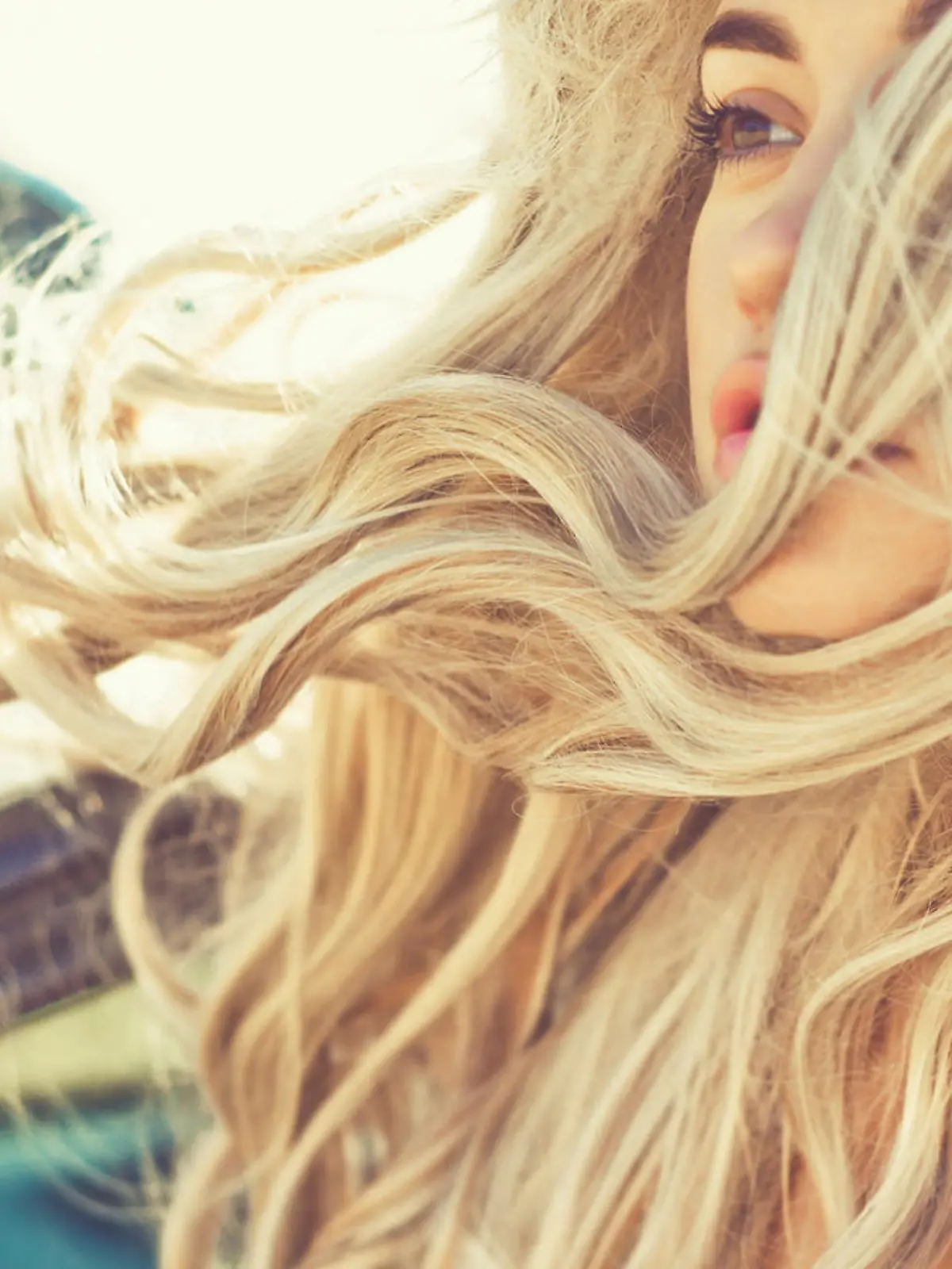 Atmospheric outdoors fashion portrait of beautiful blonde in car on the beach