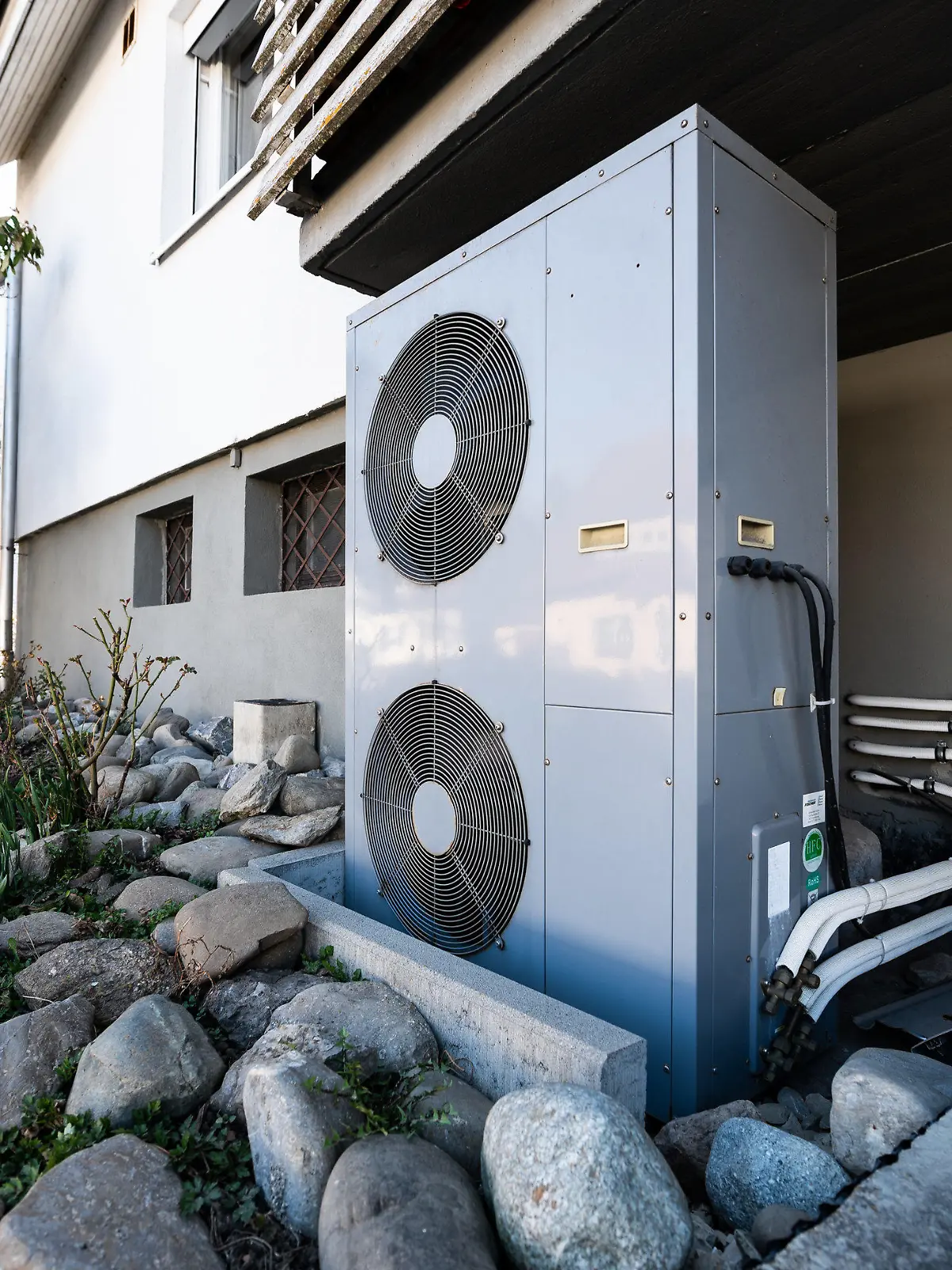 ARCHIV - 24.03.2022, Baden-Württemberg, Rottweil: Die Lüftungsanlage einer Wärmepumpe steht vor einem Wohnhaus. Ein Hindernis für den schnelleren Ausbau von Wärmepumpen sind aus Sicht zahlreicher Expertinnen und Experten Wohngebäude ohne energetische Sanierung. (zu dpa «Experten: Unsanierte Gebäude häufig Problem für Wärmepumpeneinbau») Foto: Silas Stein/dpa +++ dpa-Bildfunk +++