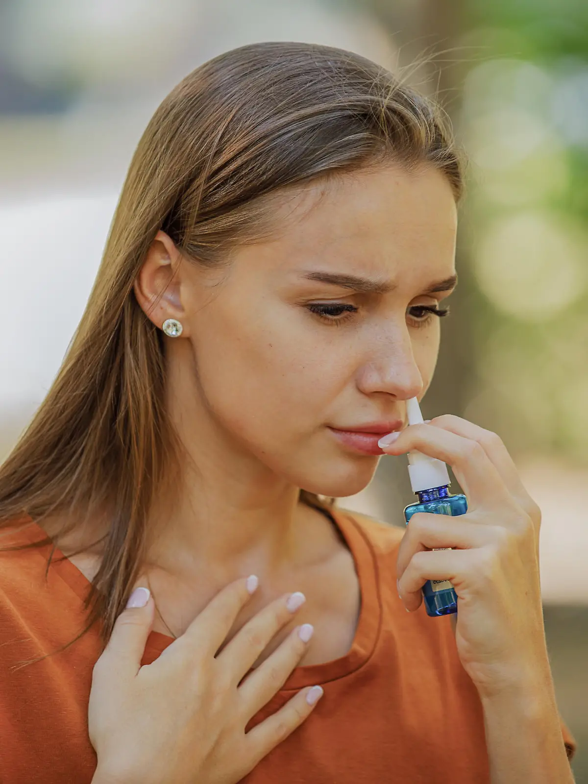 A Woman of Caucasian Ethnicity is Using Nasal Spray Due to the Problems with Nose and Breathing in the Public Park.